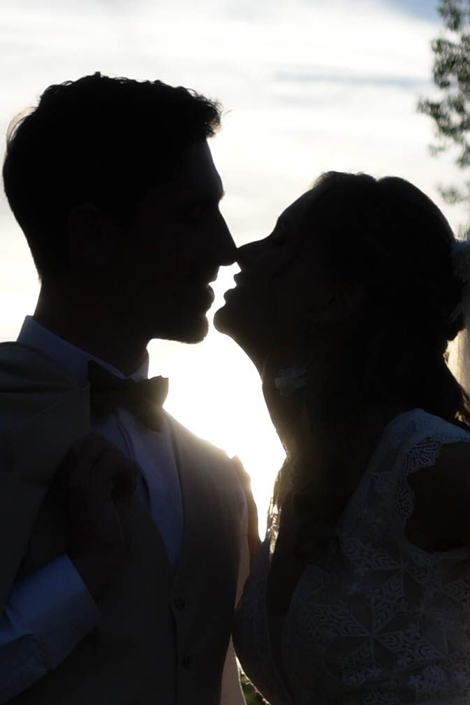 Silhouetted couple embracing in a romantic sunset moment with backlit glow creating dramatic shadows.