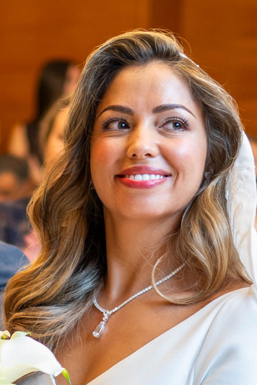 A series of four close-up photos showing someone smiling while wearing a white dress and sparkling necklace.
