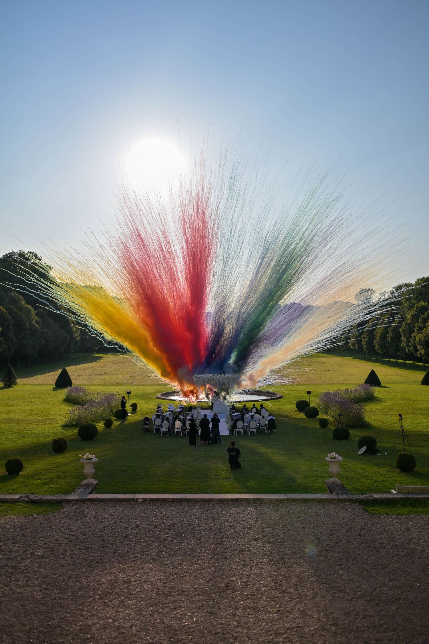 Colorful smoke explosion display on the lawn of a grand estate during an outdoor celebration.