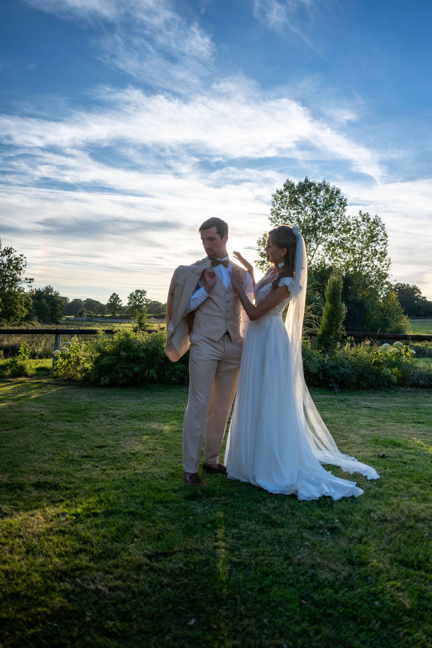 Romantic sunset wedding photography session in a grassy field with dramatic sky.
