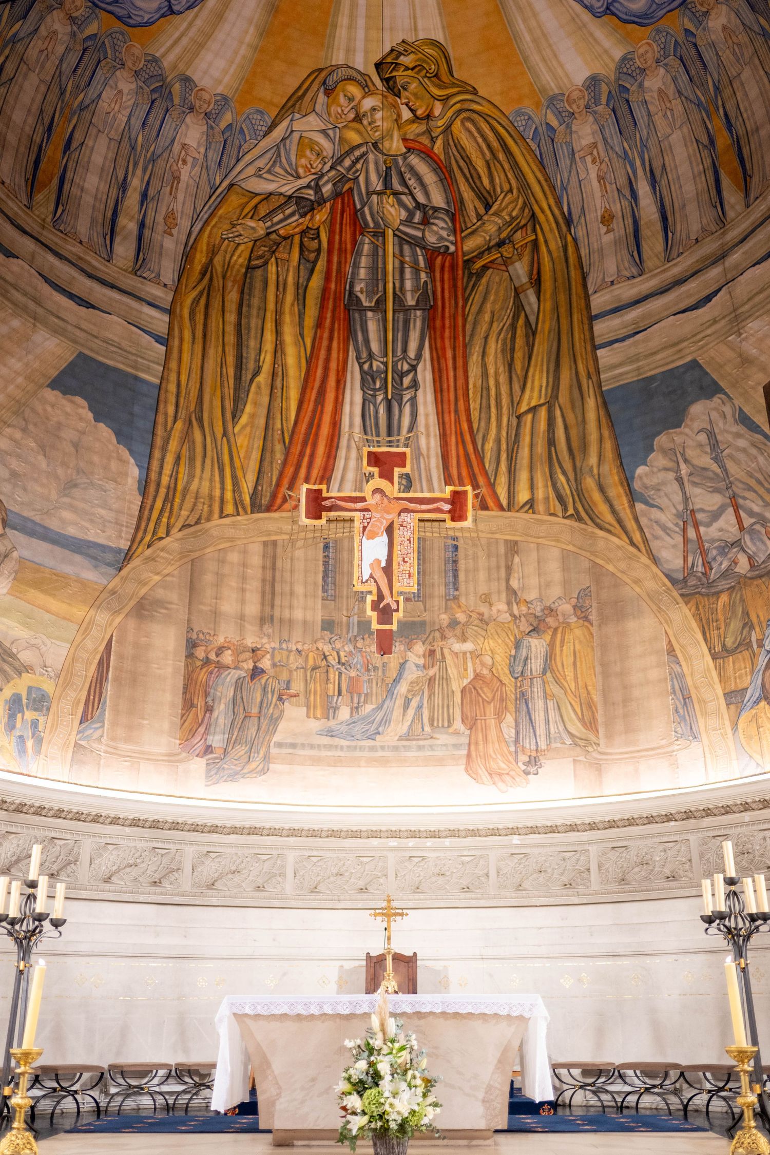 Religious mural with golden figures and crucifix painted on church ceiling dome.