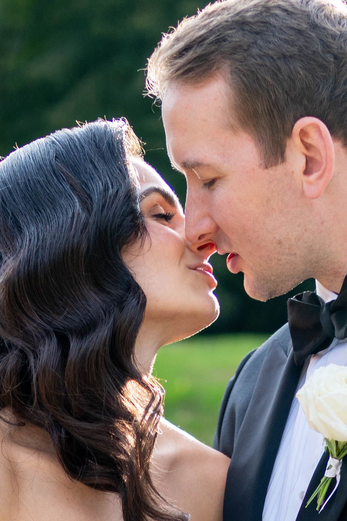 A romantic wedding couple shares an intimate moment in a garden setting.