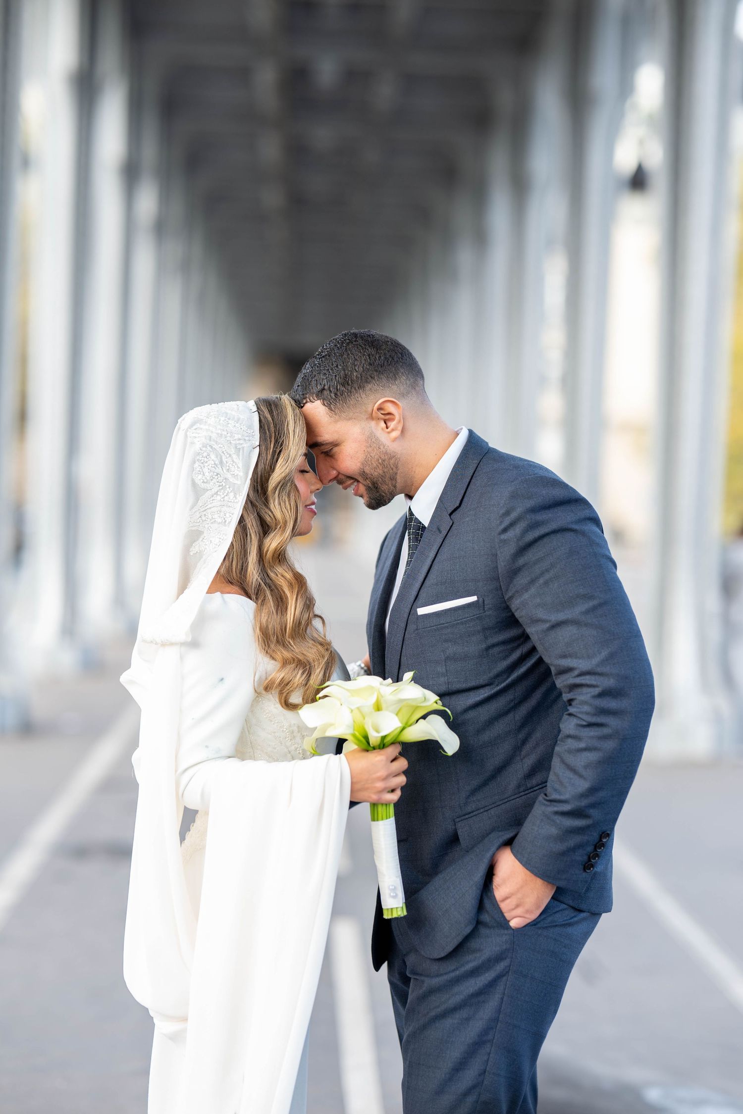 Wedding couple shares intimate moments under an architectural colonnade.