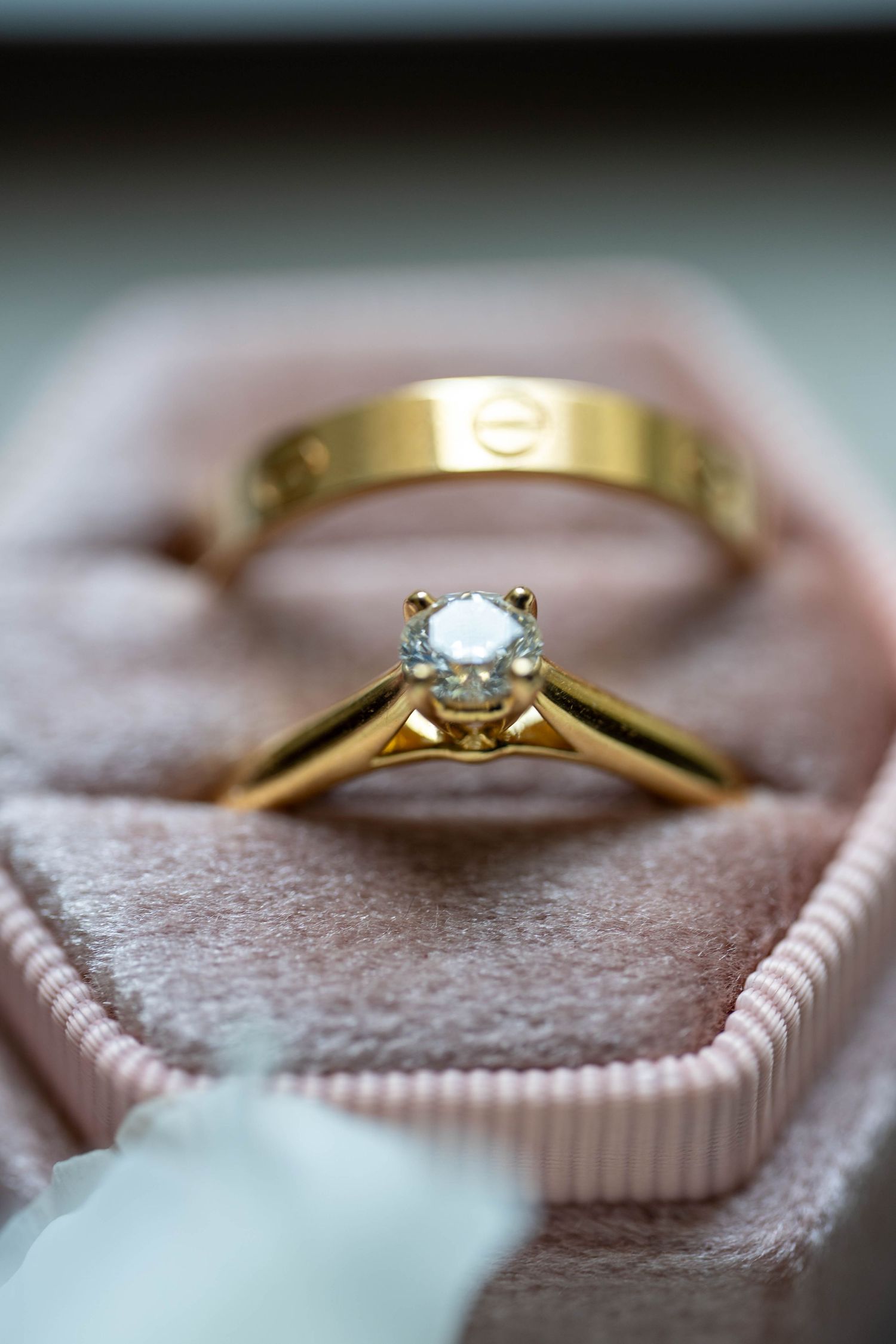 Close-up view of a delicate gold engagement ring with a small diamond solitaire resting on a chocolate dessert.