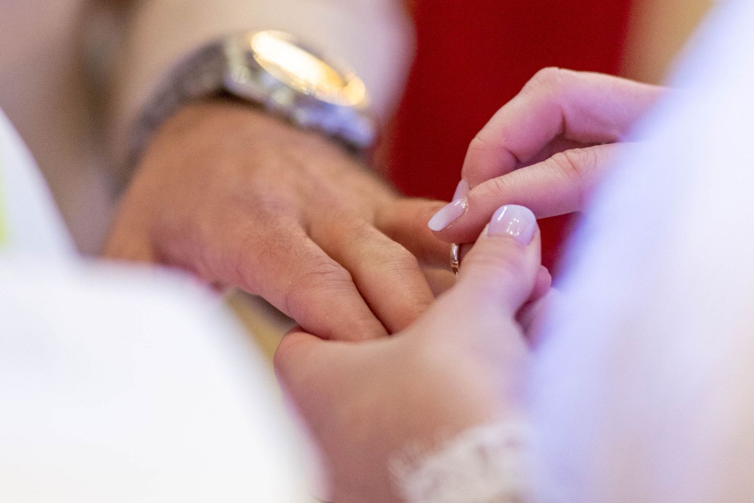 Couple signing wedding documents with a close-up view of hands holding pens on white paper.