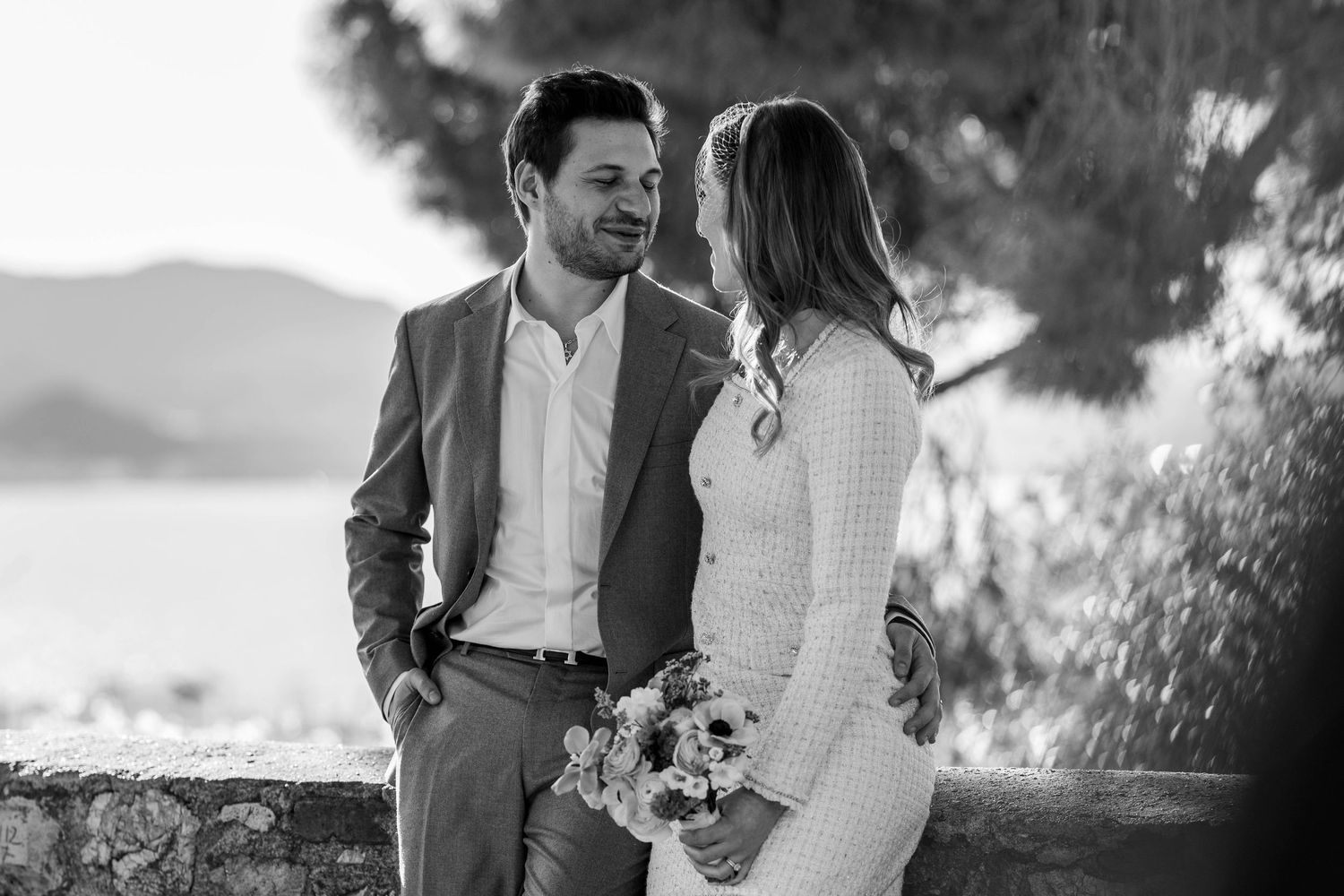 A happy couple embraces during their outdoor wedding ceremony against a scenic mountain backdrop.