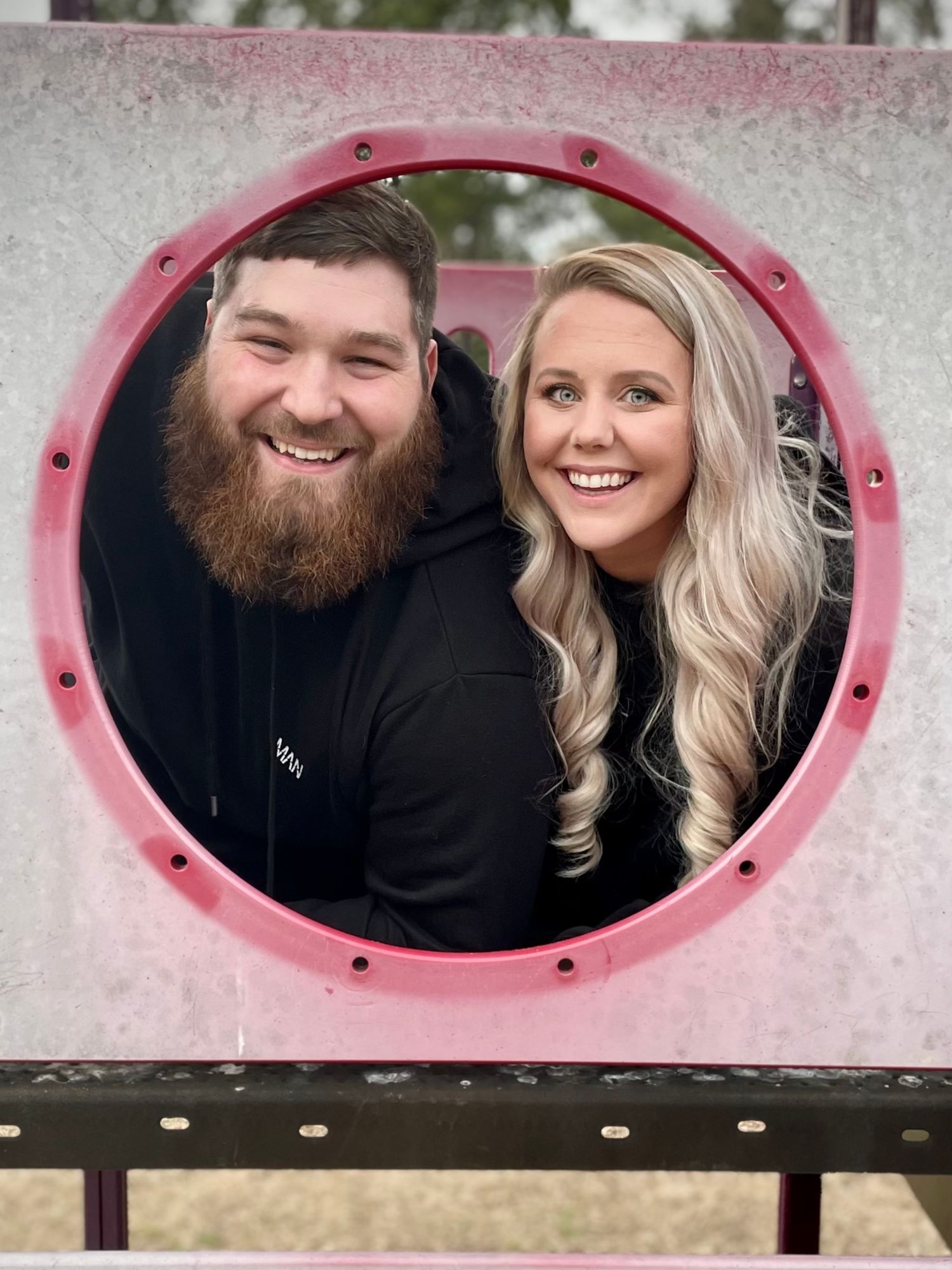 A couple poses playfully through pink circular windows in a series of black and white photographs.