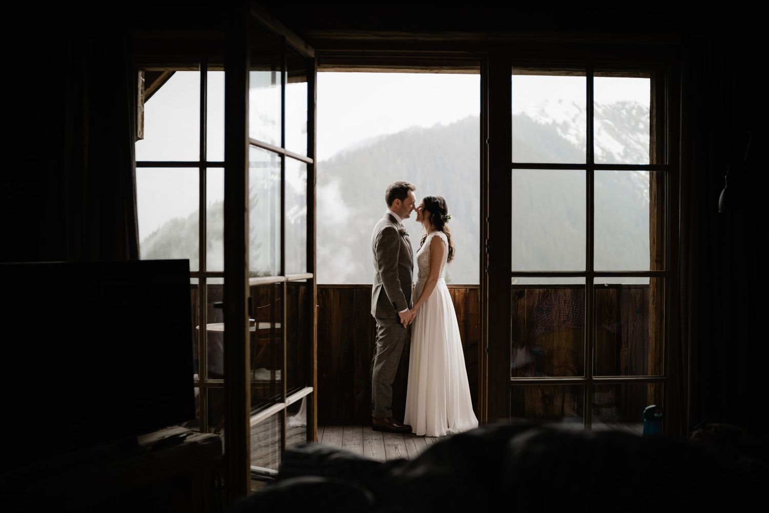 Silhouette of couple standing in window frame with mountain view.