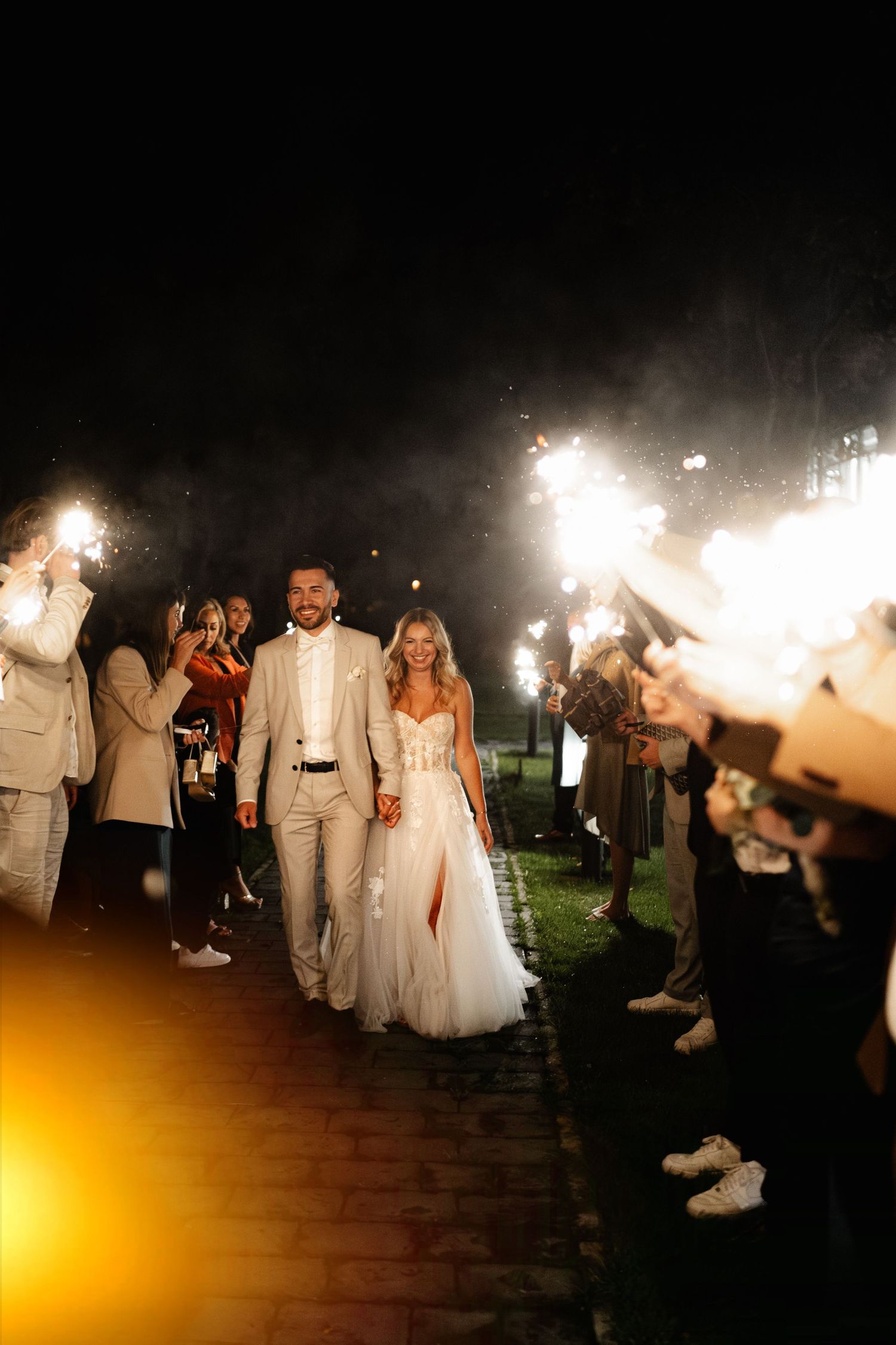 Wedding party holding sparklers creating a magical nighttime atmosphere during the couple's grand exit.
