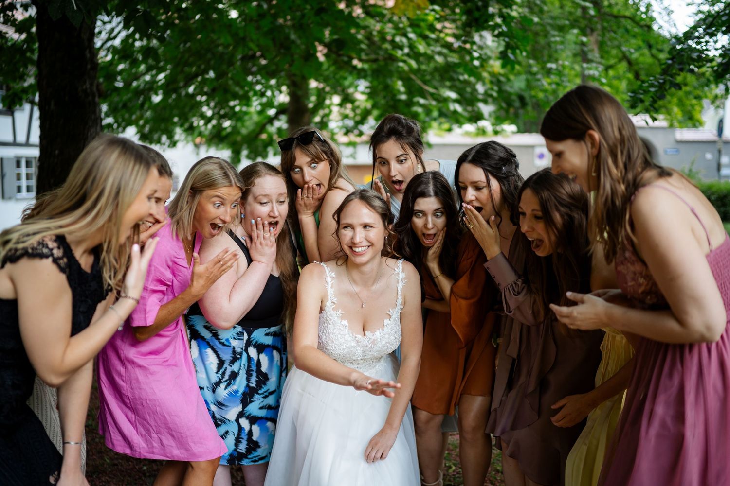 A joyful group of bridesmaids in colorful dresses share an emotional moment at a wedding celebration.