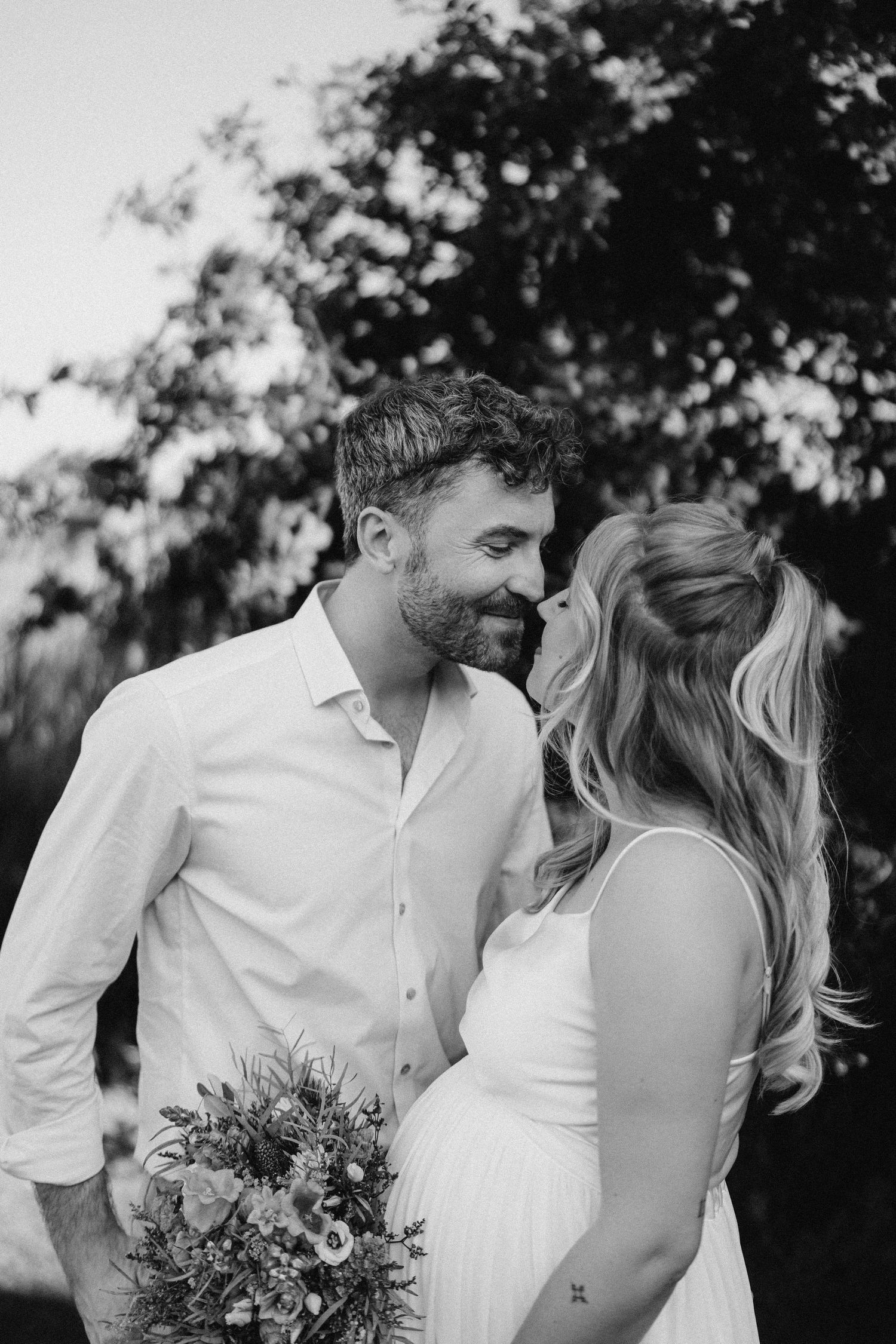 An intimate couples portrait session outdoors with a beautiful bouquet of mixed flowers.