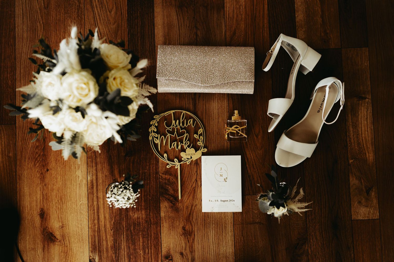 Wedding day accessories and decorations laid flat on a dark wooden surface.