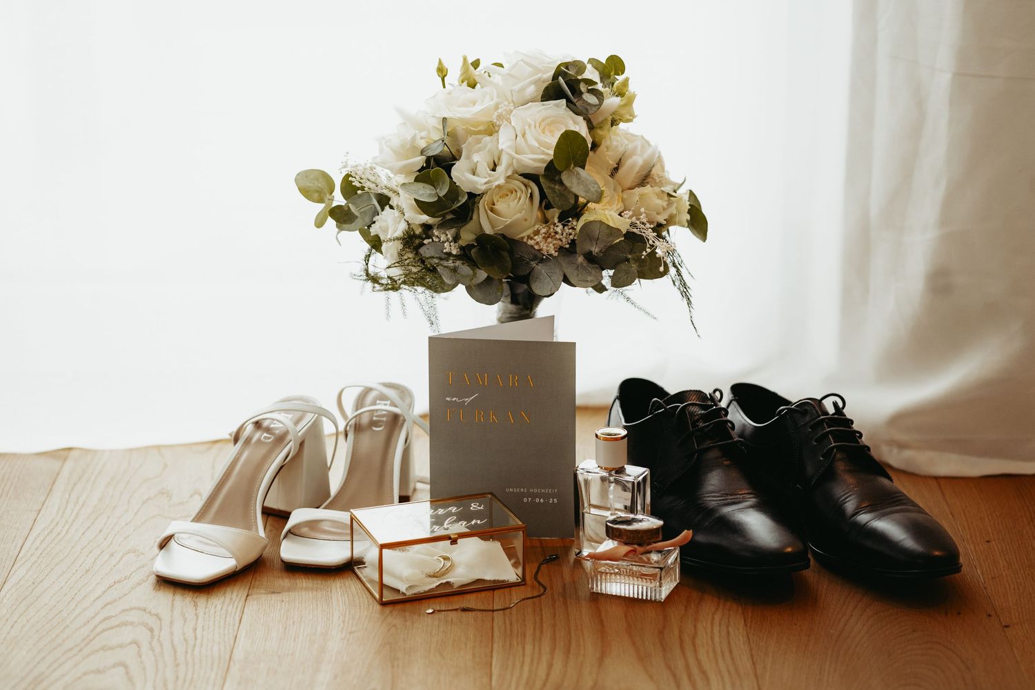 Wedding detail flatlay with white flowers, shoes and accessories on light surface.