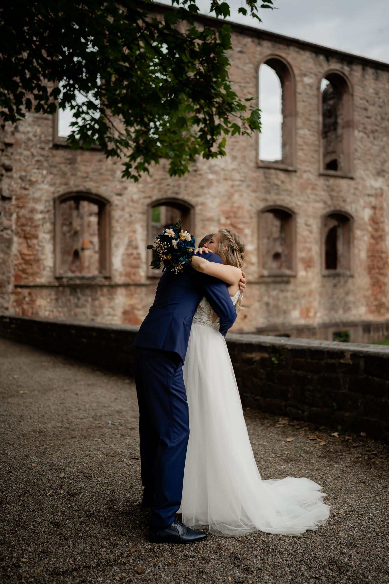A couple shares an intimate moment against the backdrop of historic stone castle ruins.