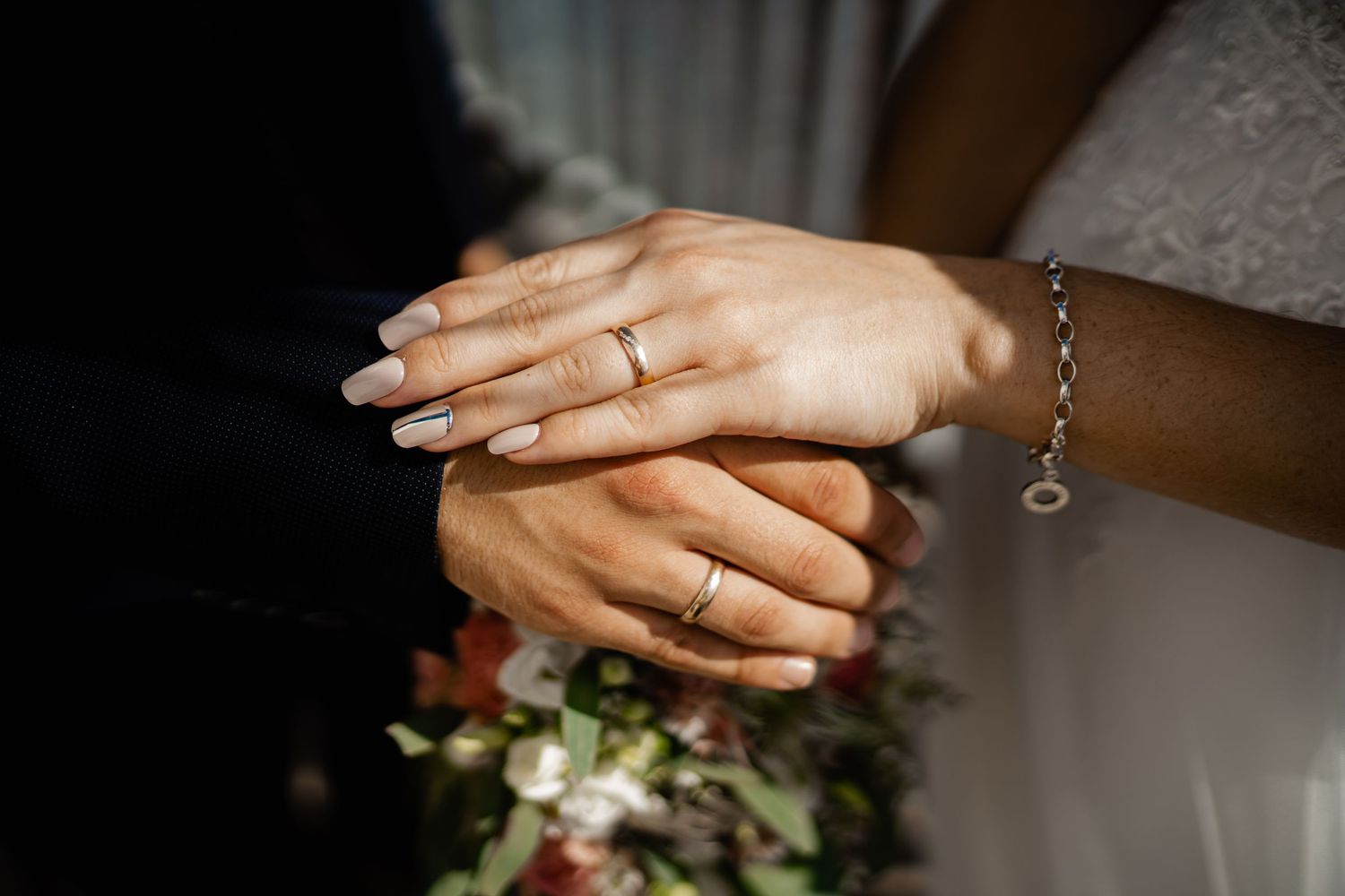 Close-up shots of hands and wedding rings with elegant floral details.