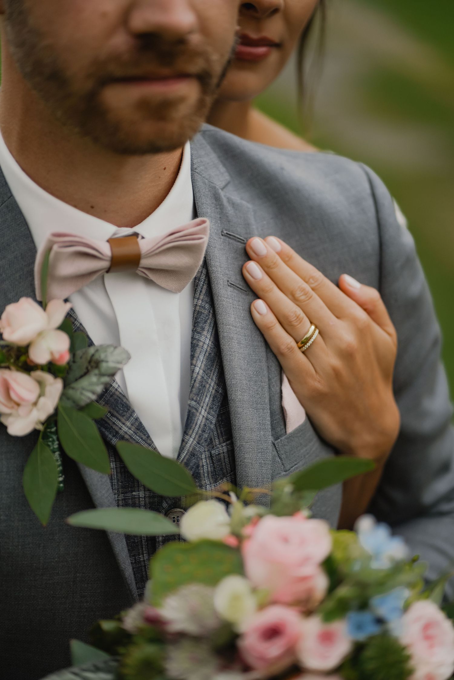 Detail shot of a groom in grey suit with pink bowtie and floral boutonniere.