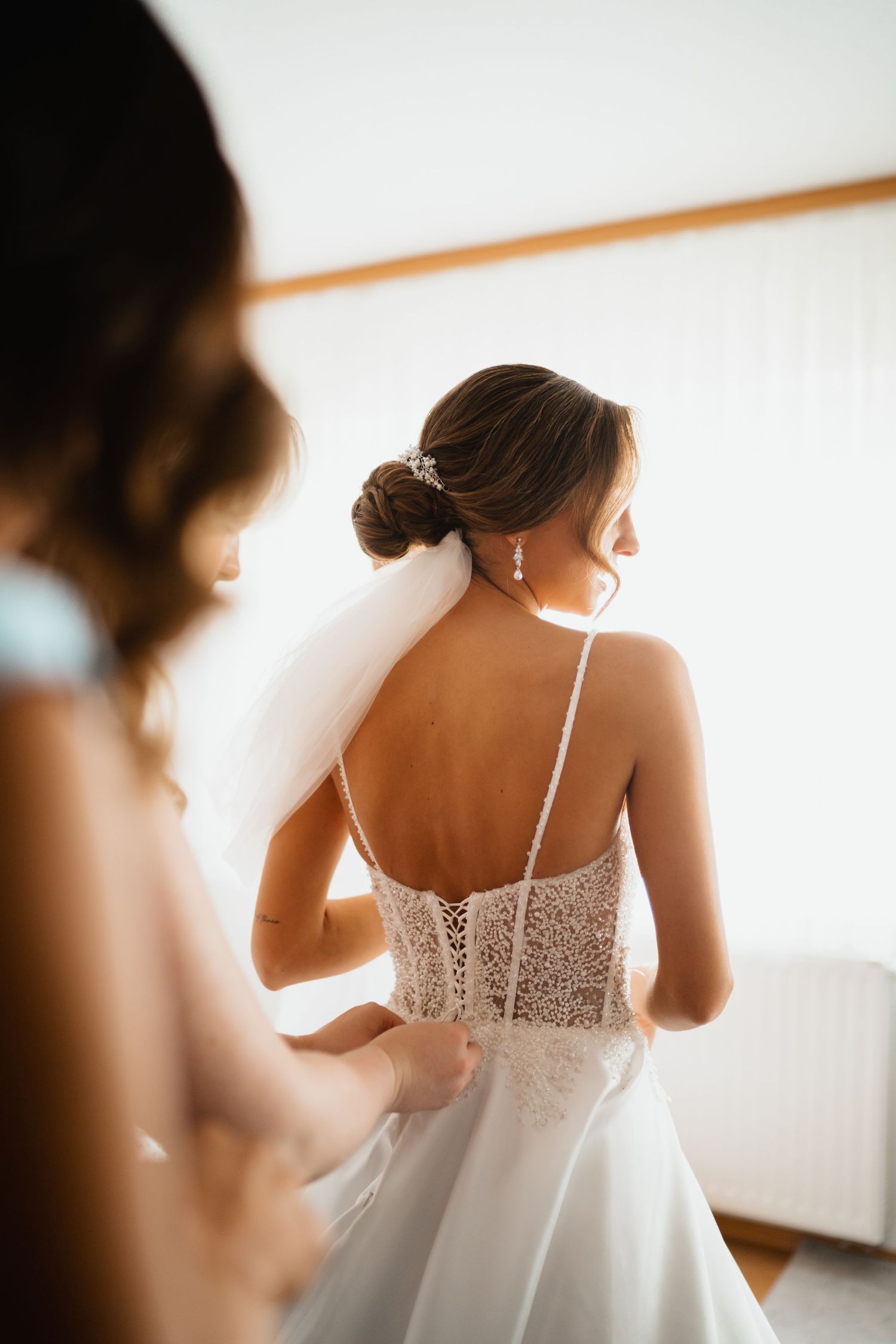 Back view of an elegant white wedding dress with intricate lace details and spaghetti straps.