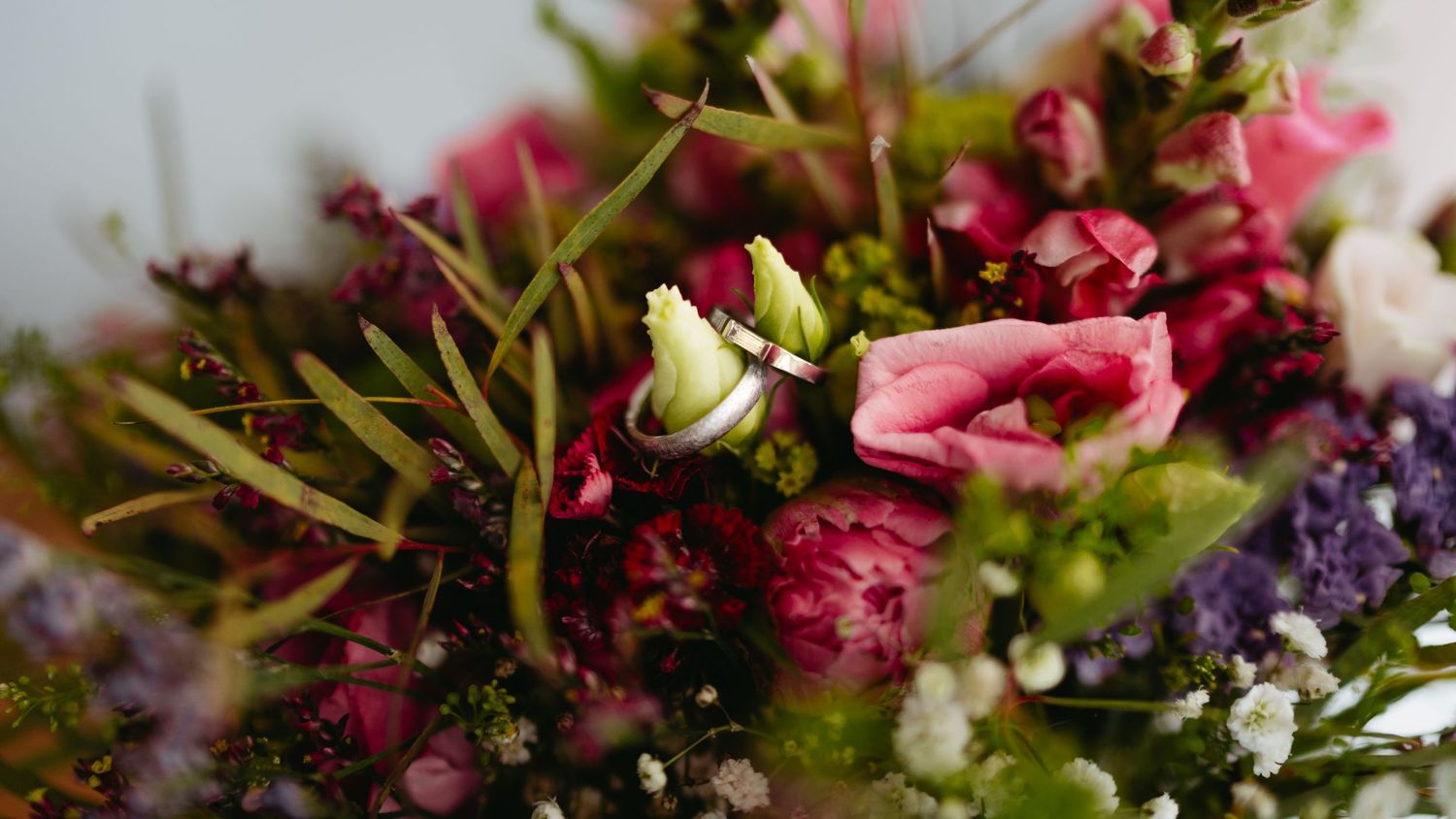 Colorful wedding bouquet featuring pink, purple, and white flowers with green foliage.