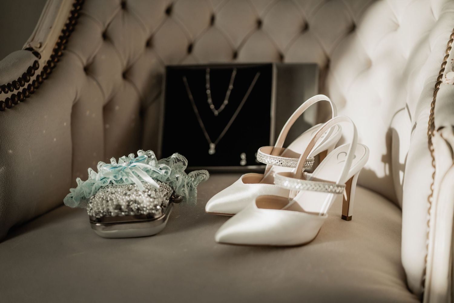 Elegant wedding accessories including white heels and a delicate tiara displayed on a neutral surface.