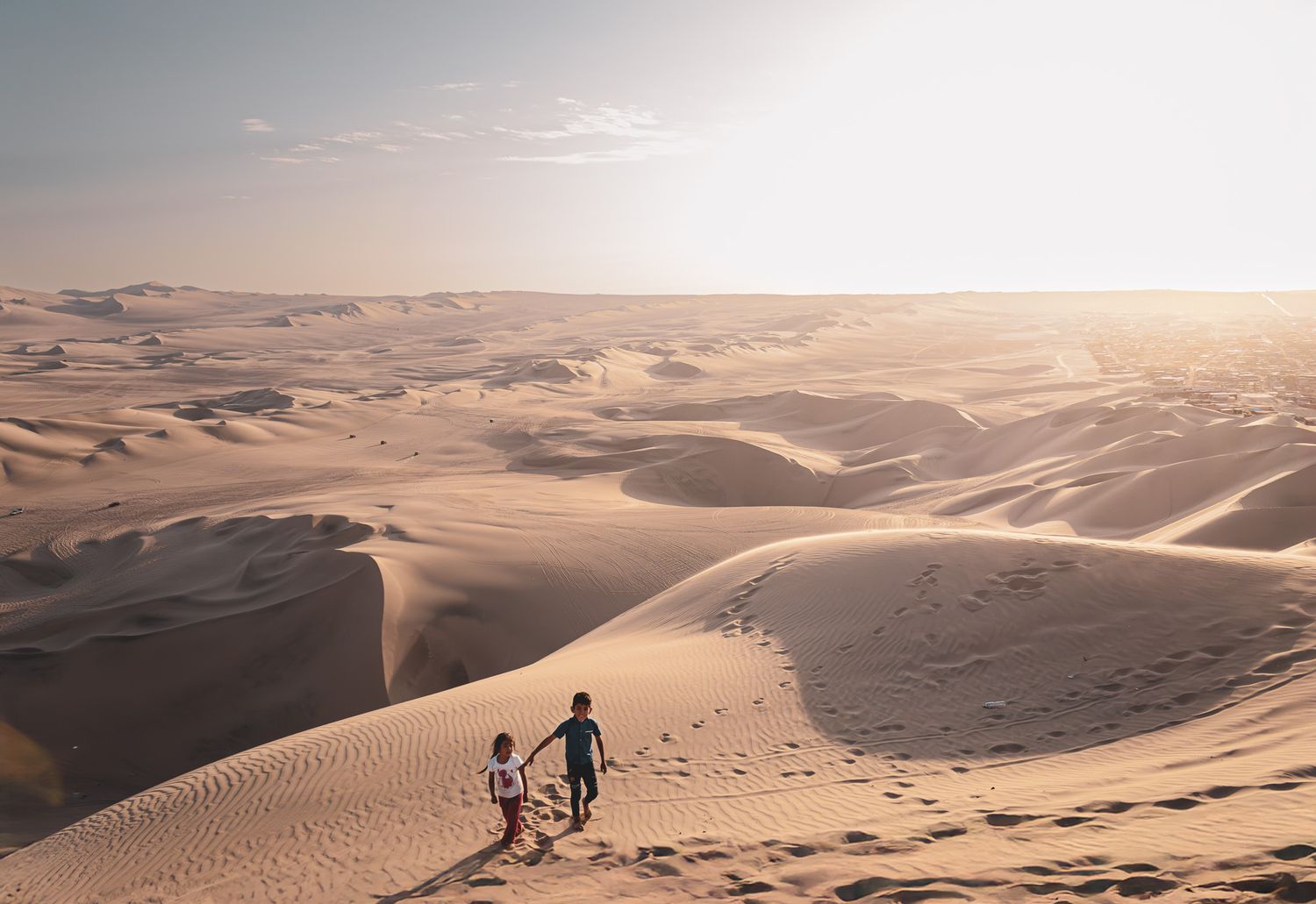 Enfants péruviens qui jouent au couché de soleil au désert de Huacachina au Pérou.