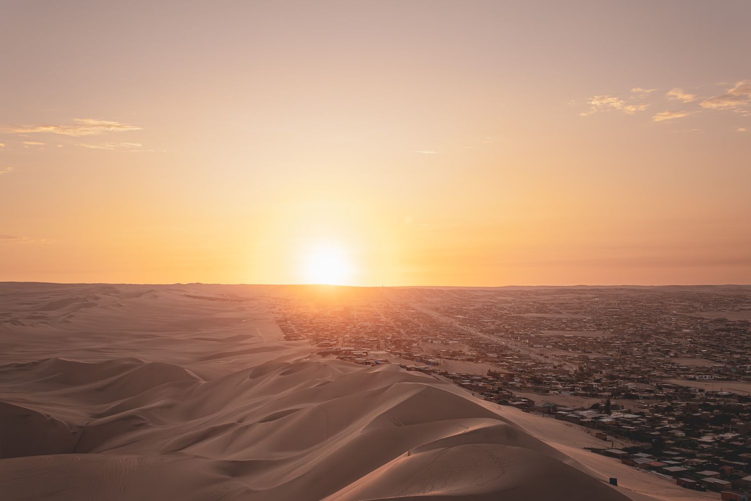Couché de soleil au désert de Huacachina au Pérou entre ville et désert.