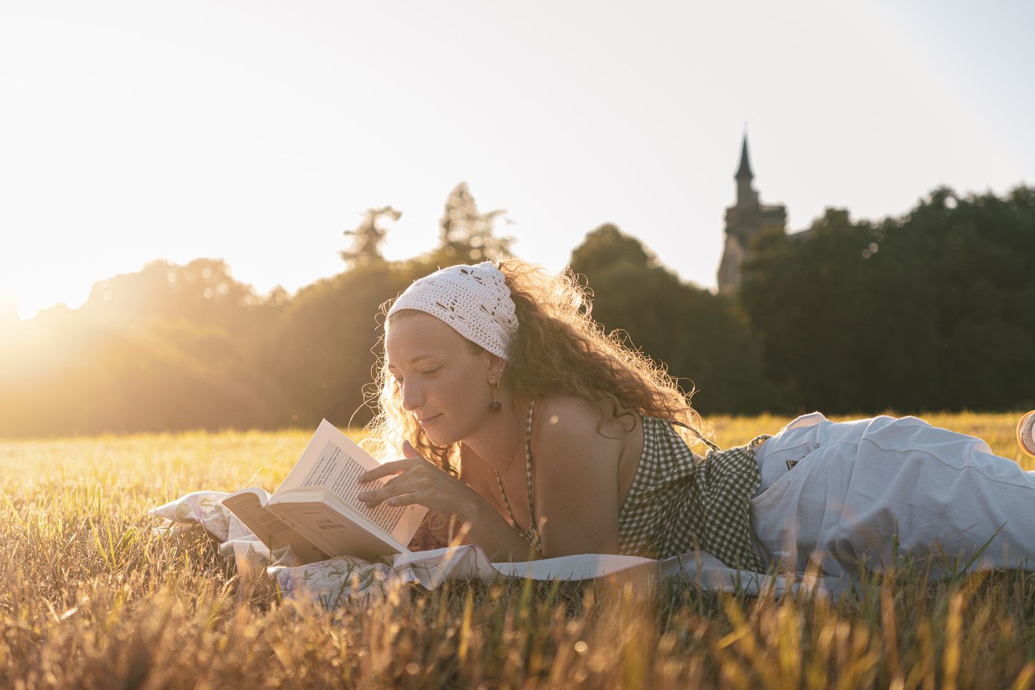 Fille qui lit un livre dans l'herbe de manière bucolique
