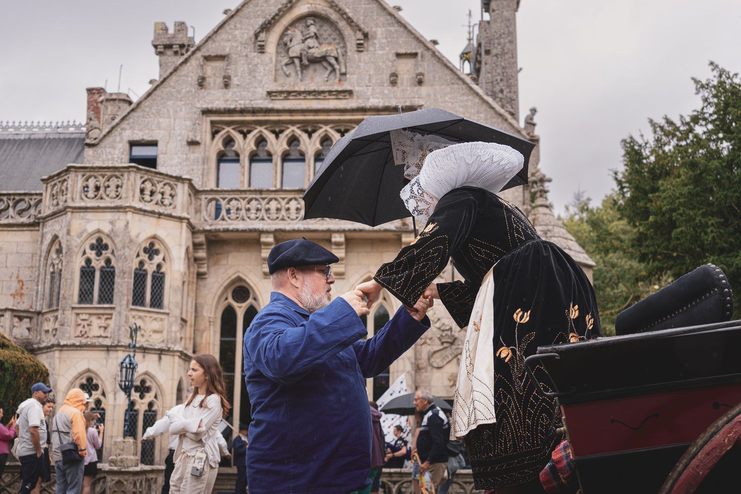 Photo de mariage devant une église avec des invités sous la pluie à Beuzec-Conq