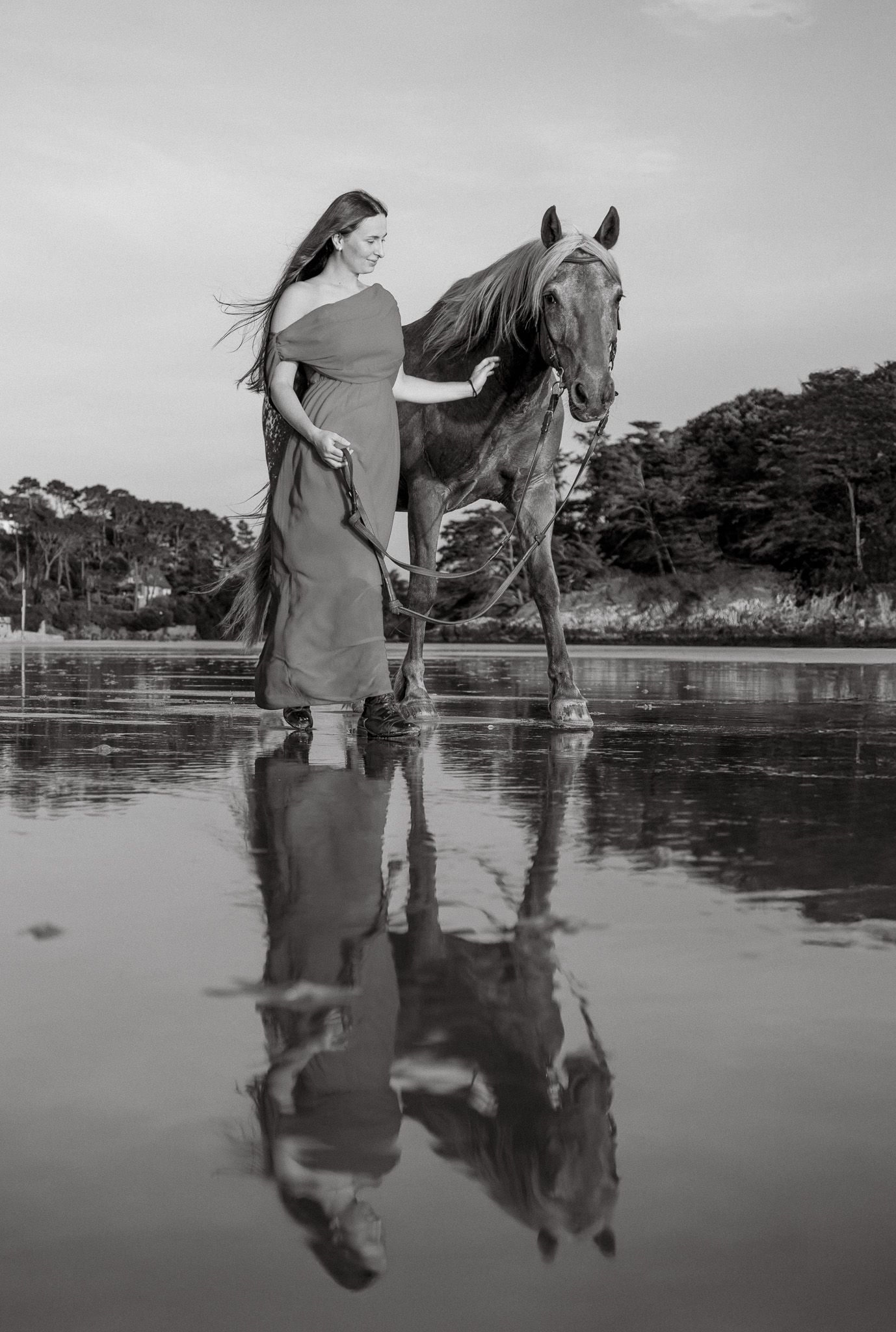 Photographie noir et blanc d’un cheval et sa cavalière au bord de l’eau