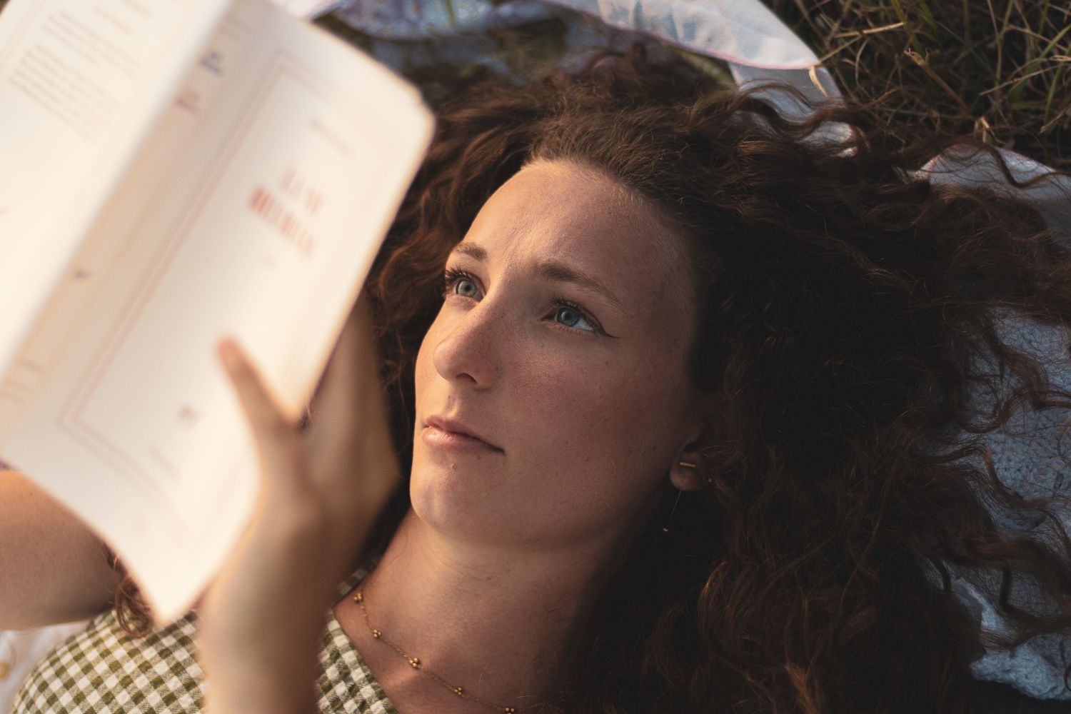 Fille qui lit un livre dans l'herbe de manière bucolique