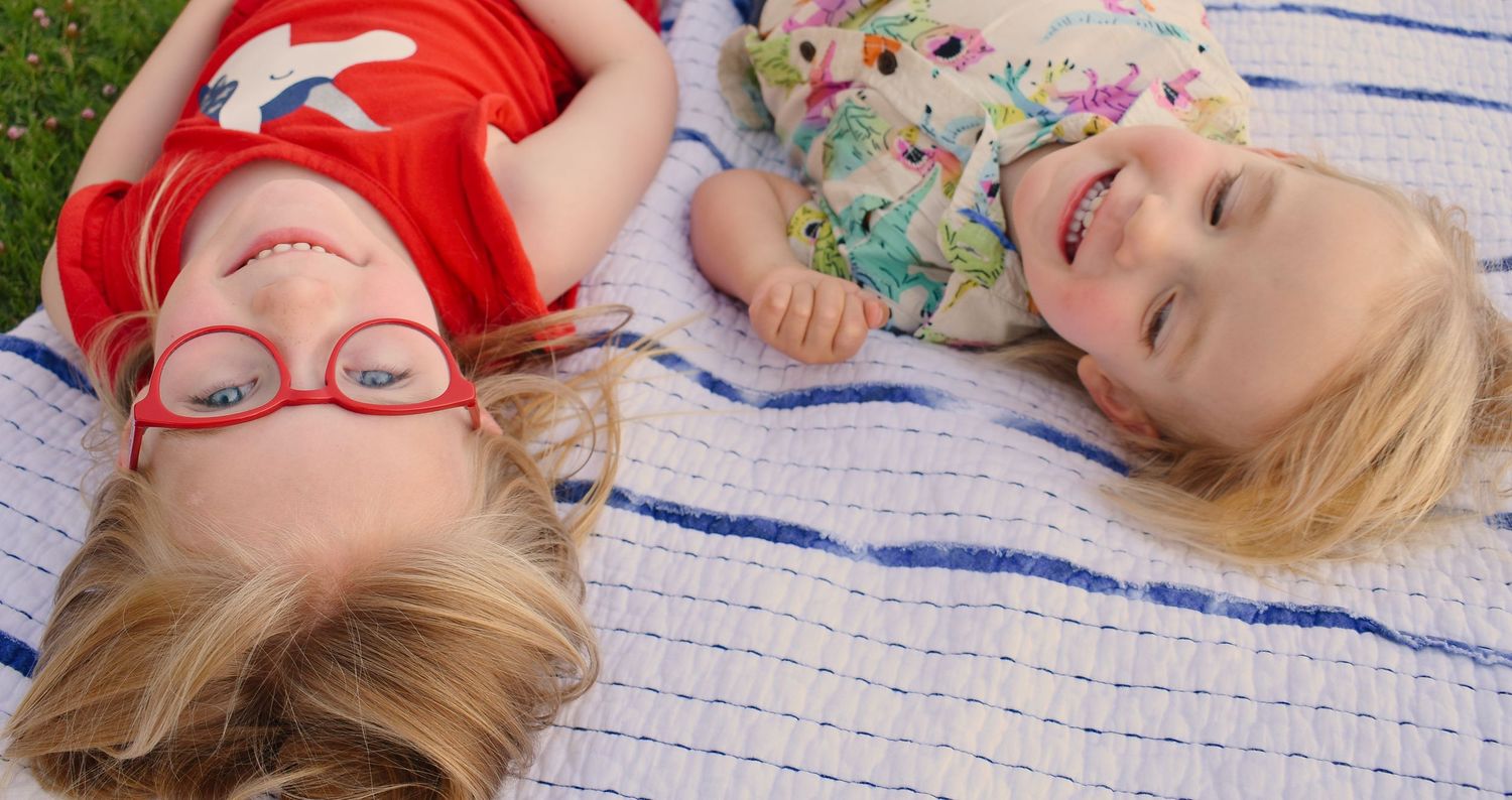 Children lying on a blue and white striped blanket in a playful pose.