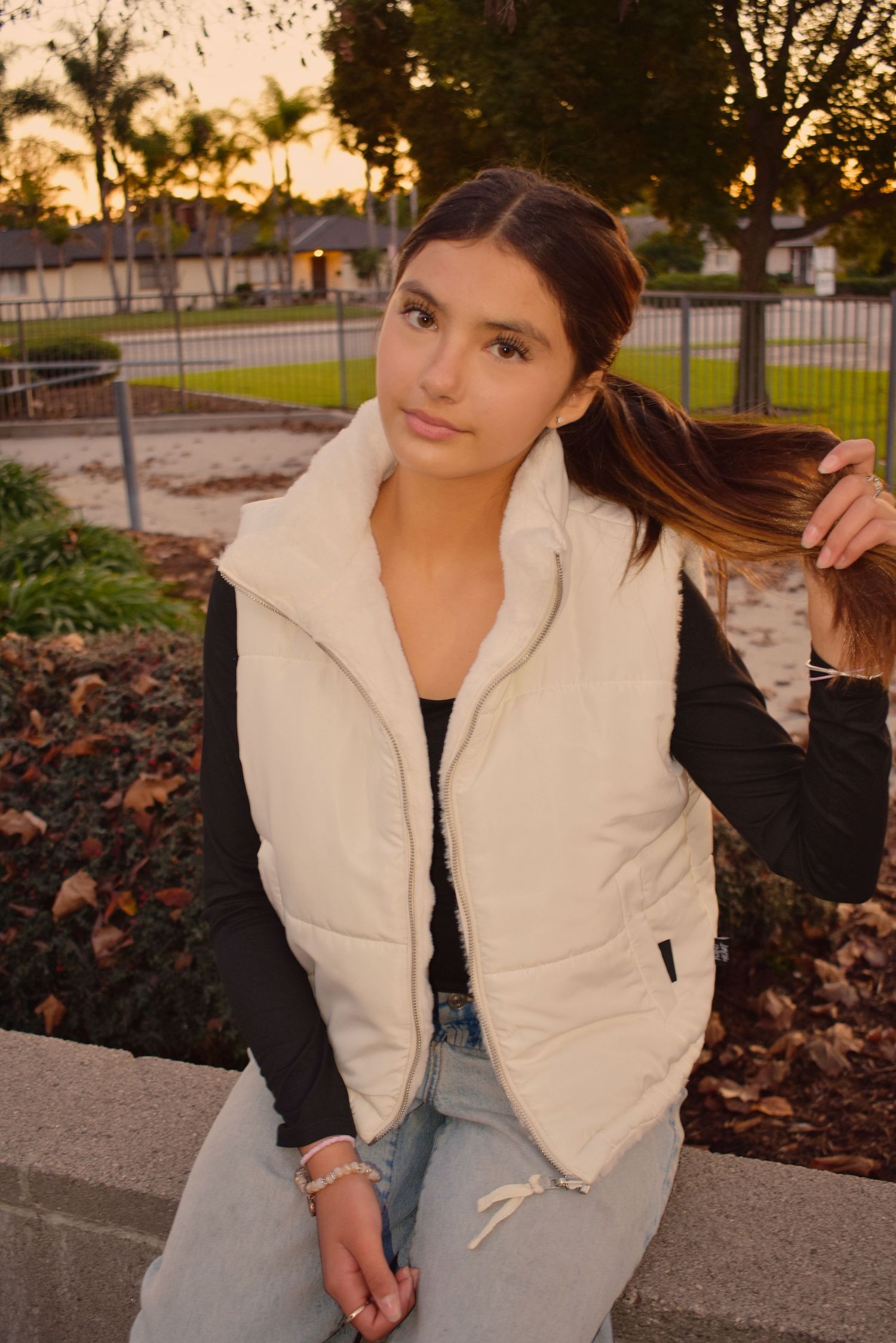 Outdoor photoshoot at sunset wearing a white puffy vest and casual attire.