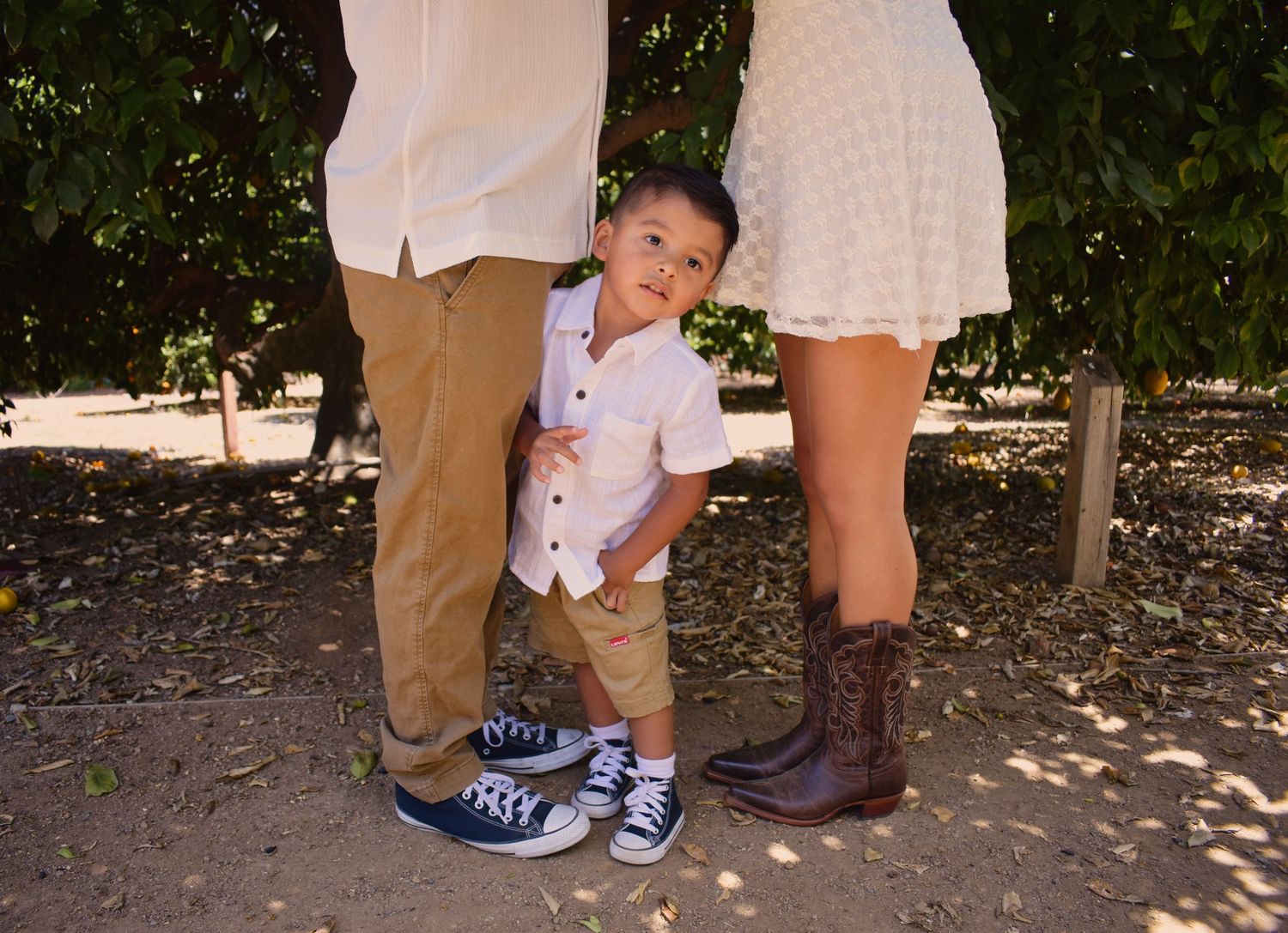 Close-up of shoes and feet of family members dressed in white and beige.