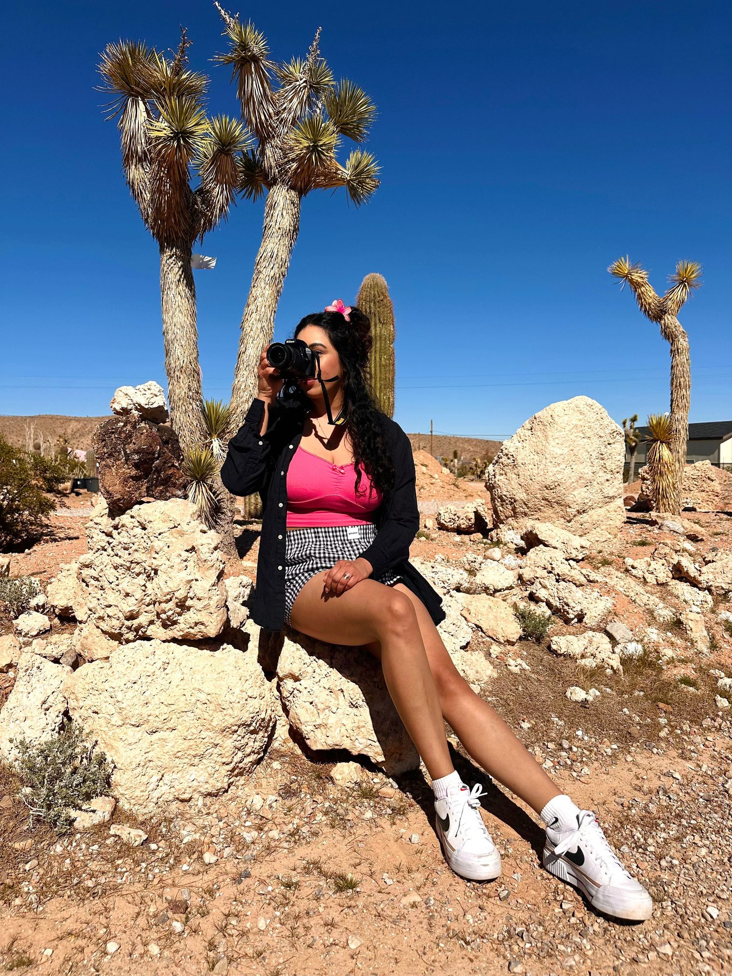 A series of photos showing legs in white sneakers sitting on rocky desert terrain with Joshua Trees in the background.
