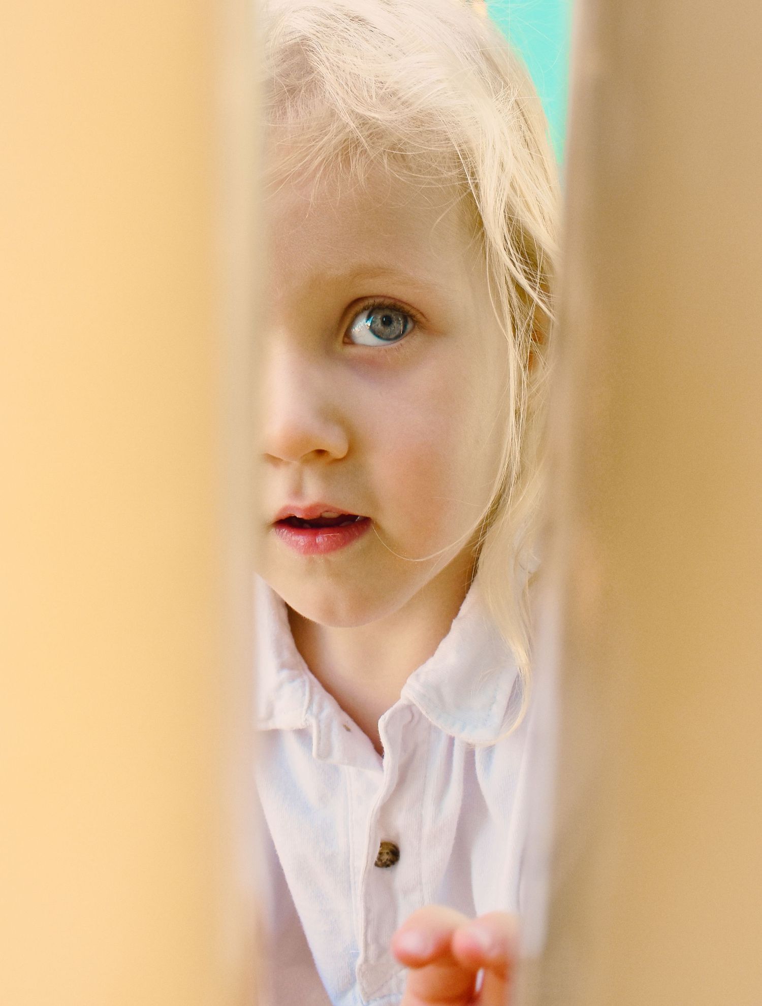 A series of four close-up portraits showing a child with blonde hair and a white collared shirt against a beige background.