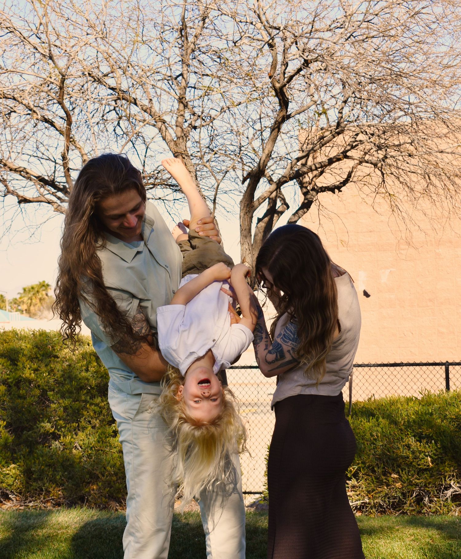 Playful dance moves and dips create joyful moments against a sunset backdrop with bare trees.