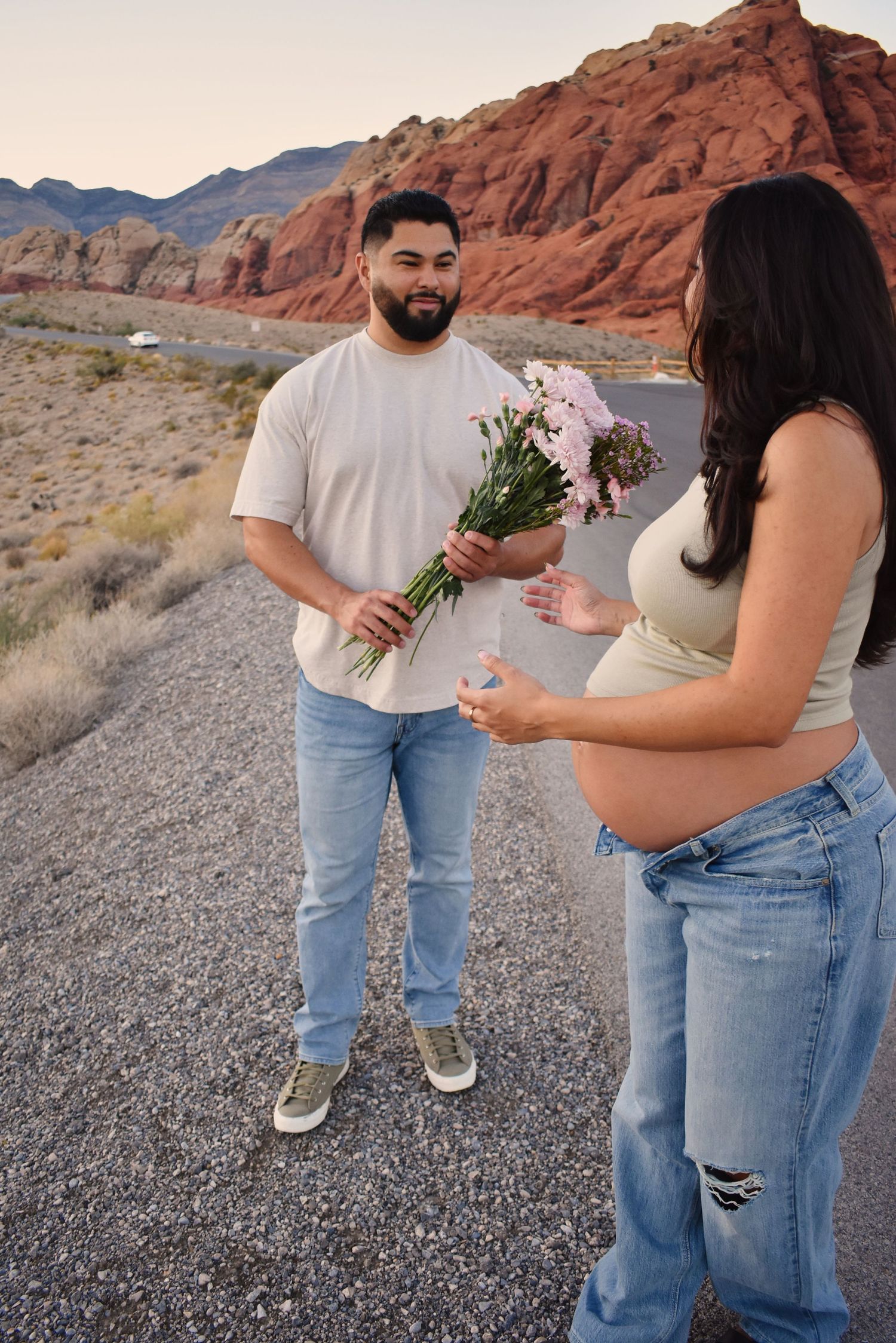Couple sharing flowers against red rock formations in desert landscape.