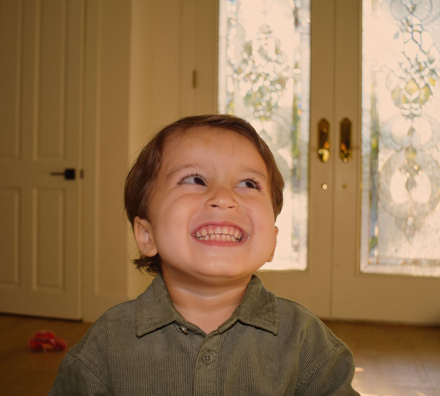 Child shows joyful expressions while sitting indoors in warm lighting.