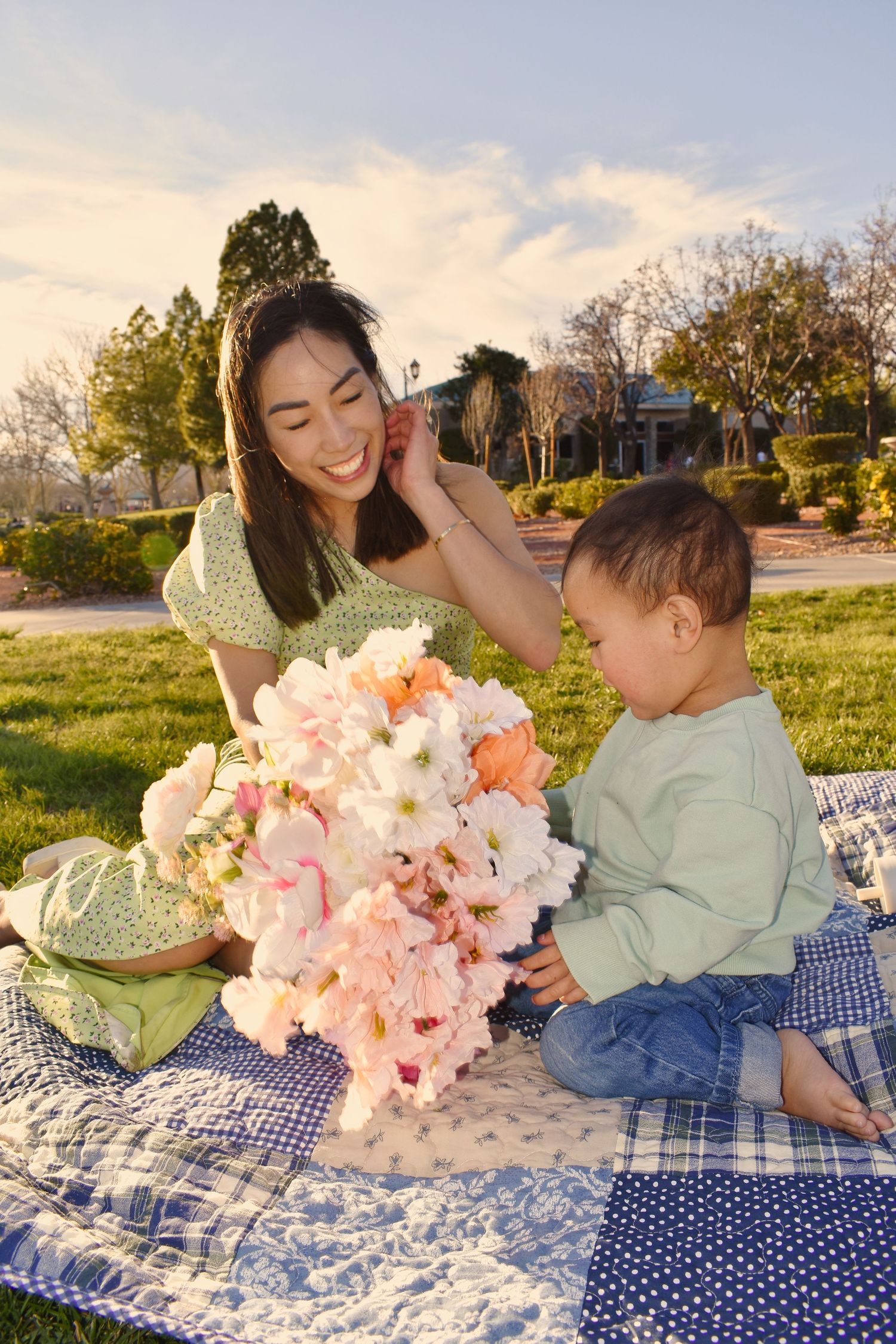 A tender moment shared on a polka dot picnic blanket with pink flowers in a sunny outdoor setting.