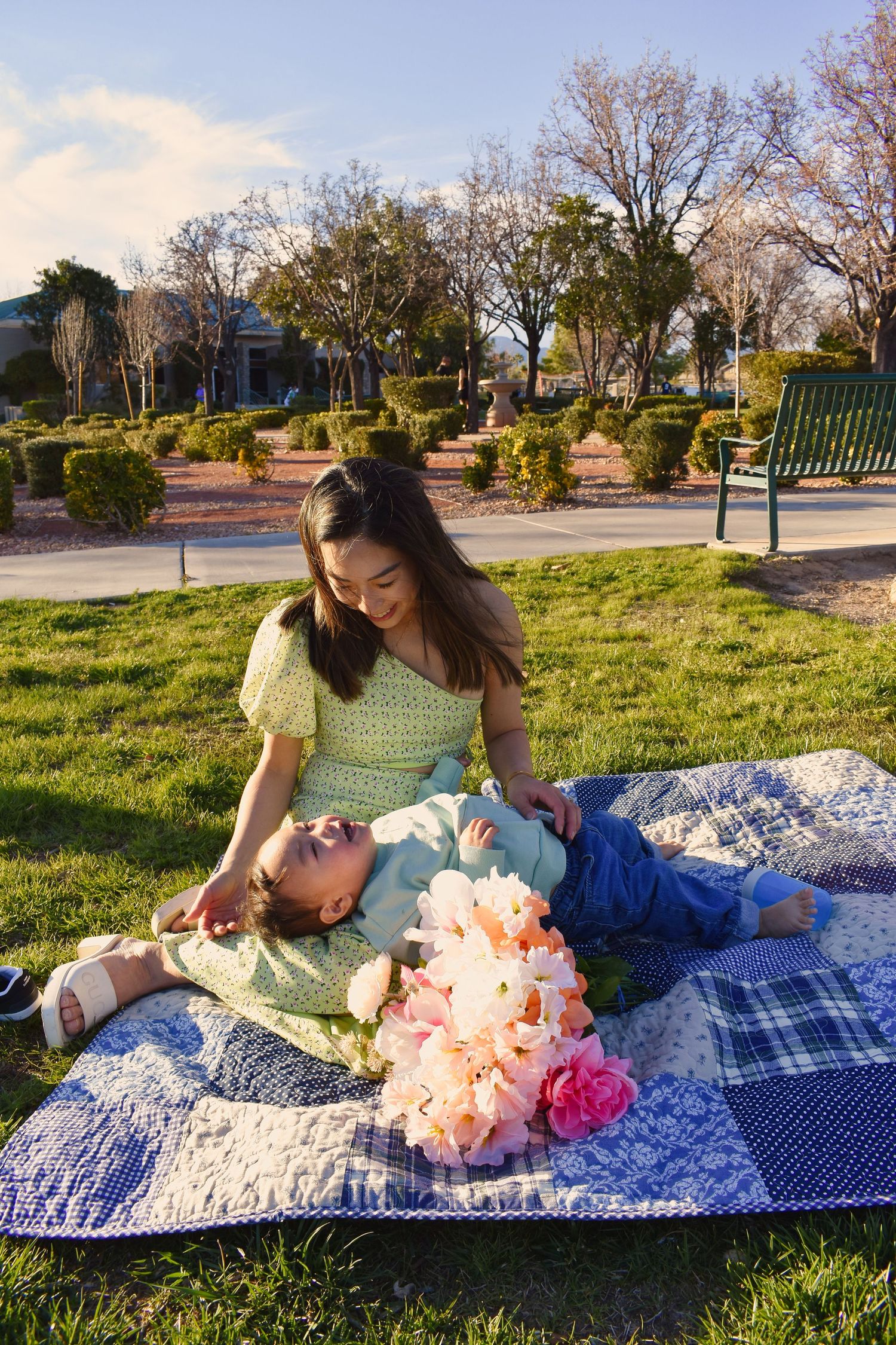 A couple relaxes on a blue and white blanket in a sunny park during springtime.