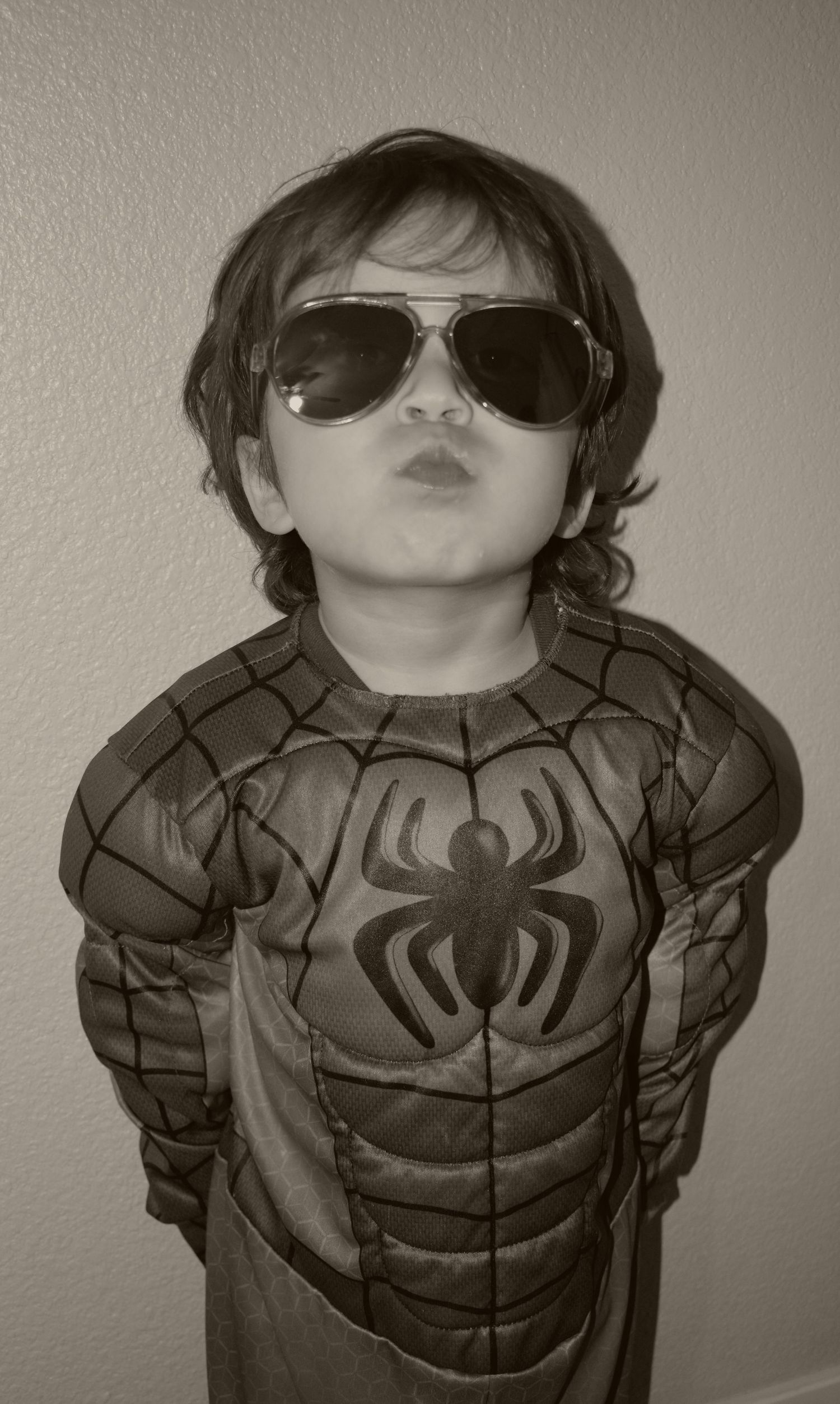 A black and white portrait showcasing a Spider-Man costume with aviator sunglasses.