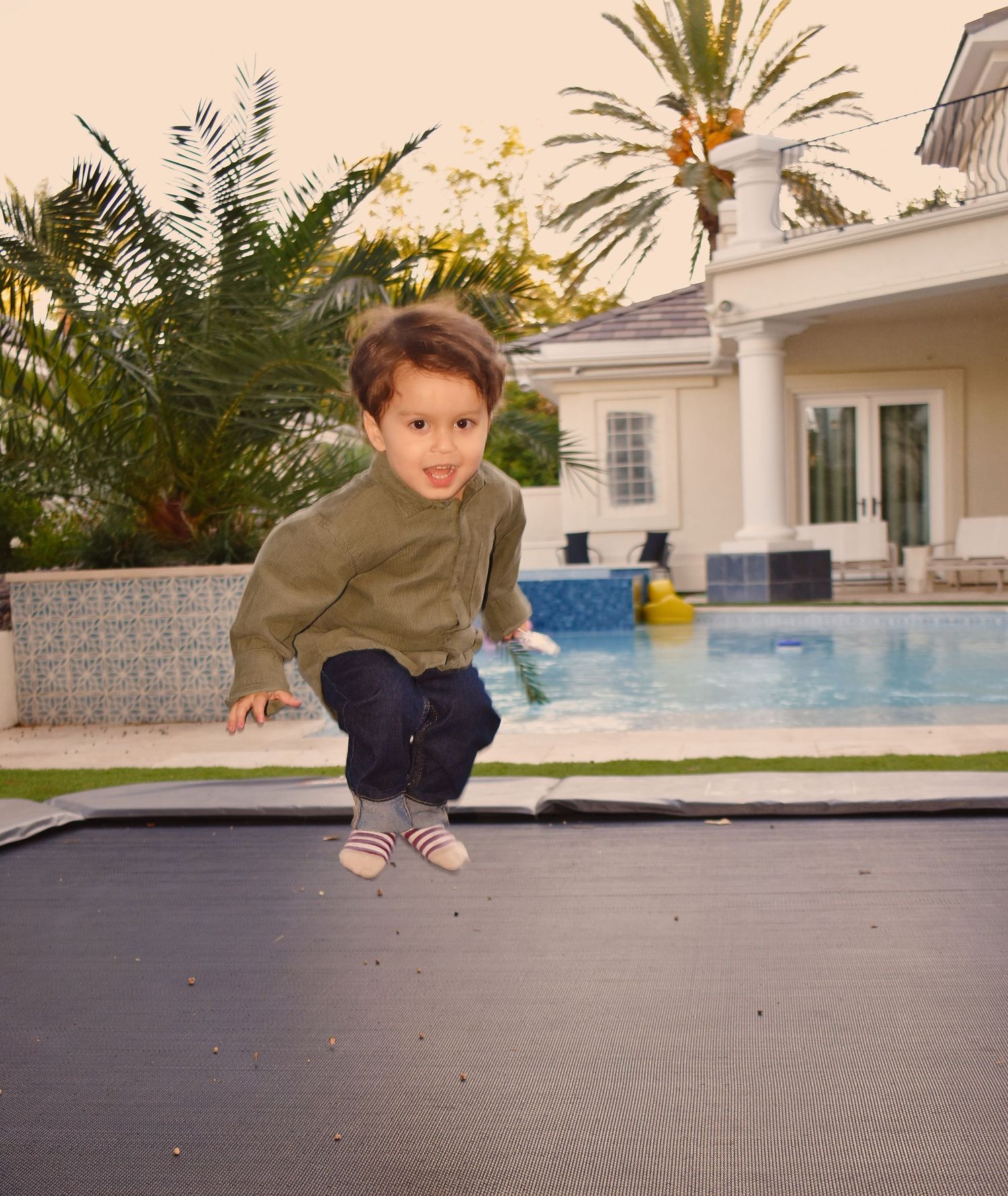 A sequence of jumping movements captured in motion against a white building and pool background.
