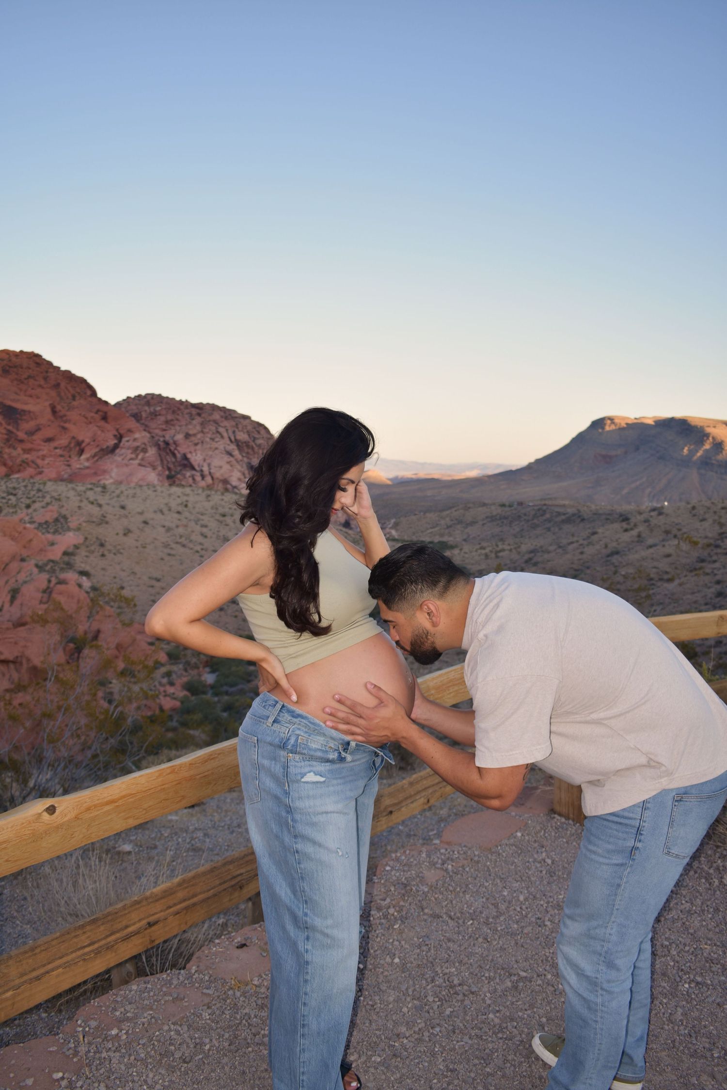 A maternity moment captured against scenic red rock mountains during sunset.