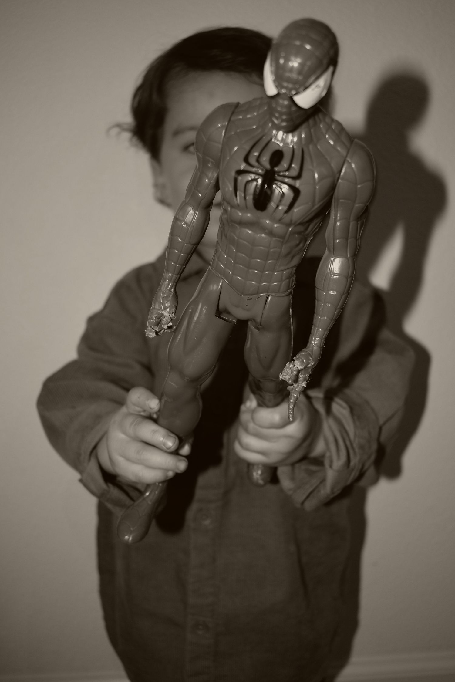Child plays with action figures in dramatic black and white photography series.