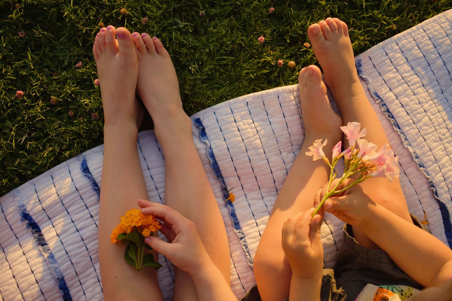 Bare feet arranged with orange flower petals on stone pavement.