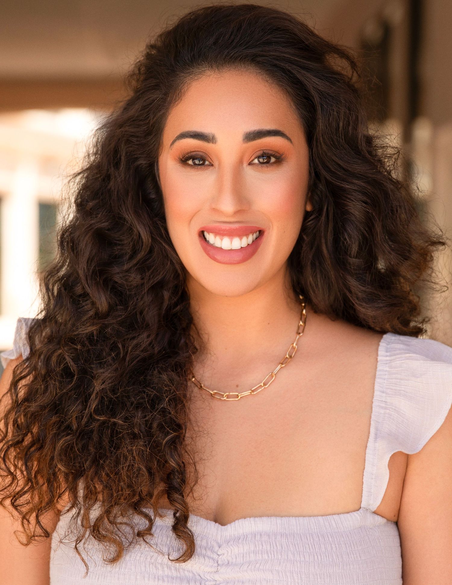 A series of headshots showing curly hair and a white top against a warm-toned background.