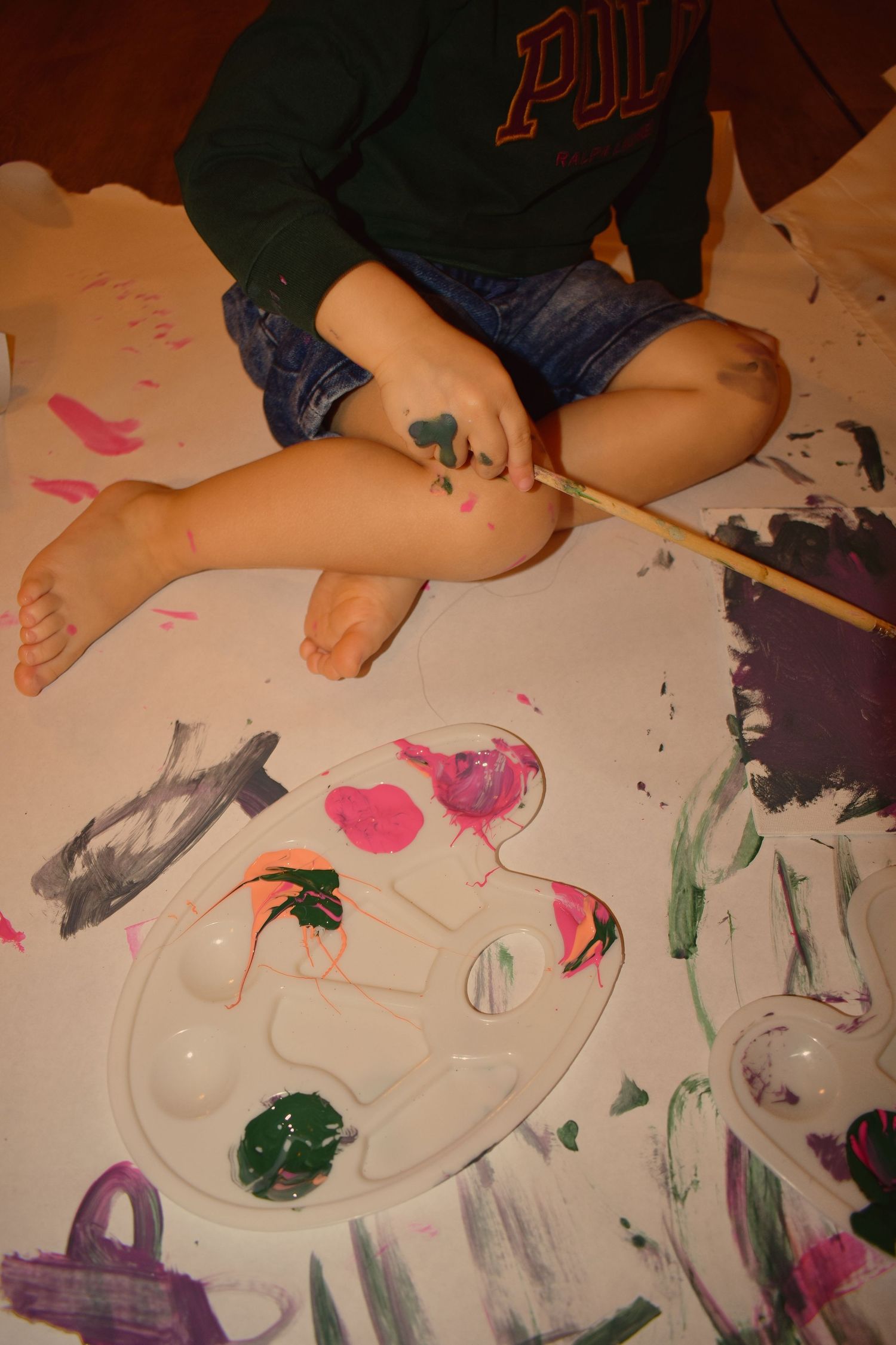 Paint splatters and artwork created on white paper during messy play session.
