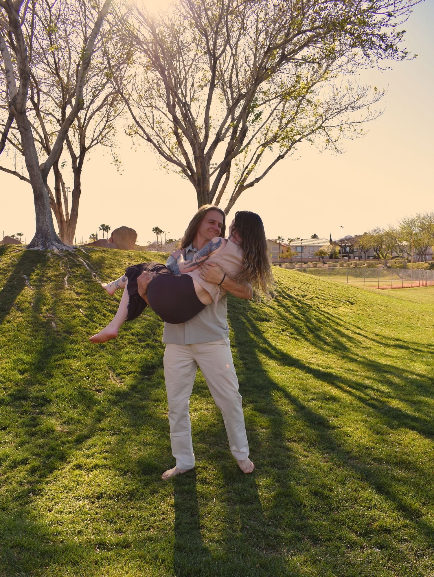 A person in white clothing performs a cartwheel sequence on a grassy hill at sunset, casting long shadows.