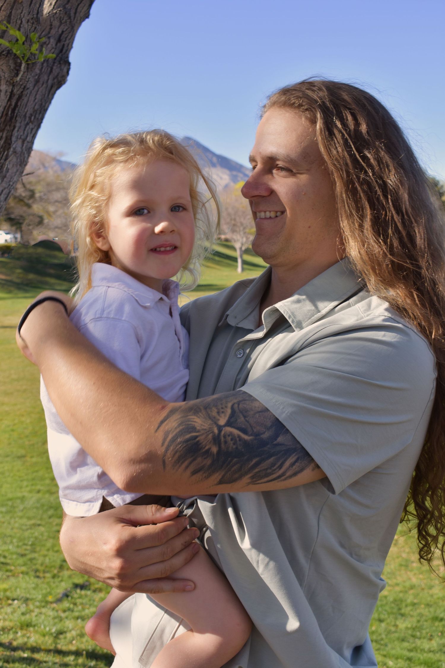 A tender moment captured between parent and child playing together outdoors on a sunny day in a grassy field.