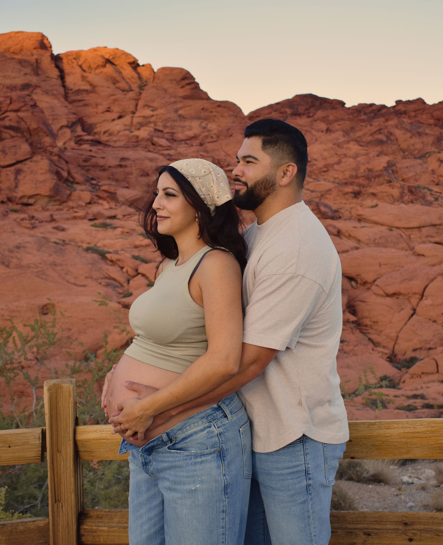 An intimate maternity portrait against red rock cliffs during sunset.