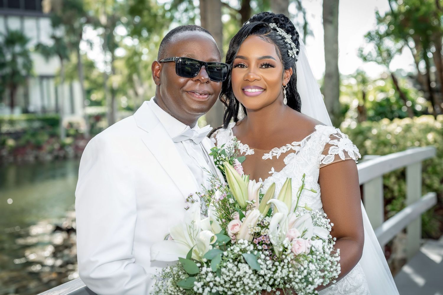 Happy couple in white attire shares intimate moment while holding delicate floral bouquet.